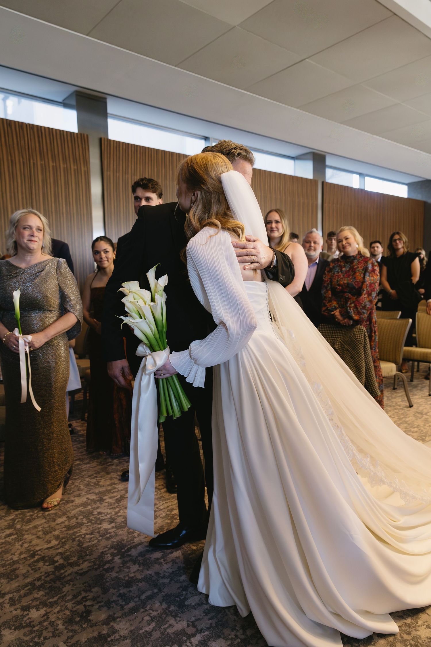 Wedding reception guests gather around bride in flowing white gown.