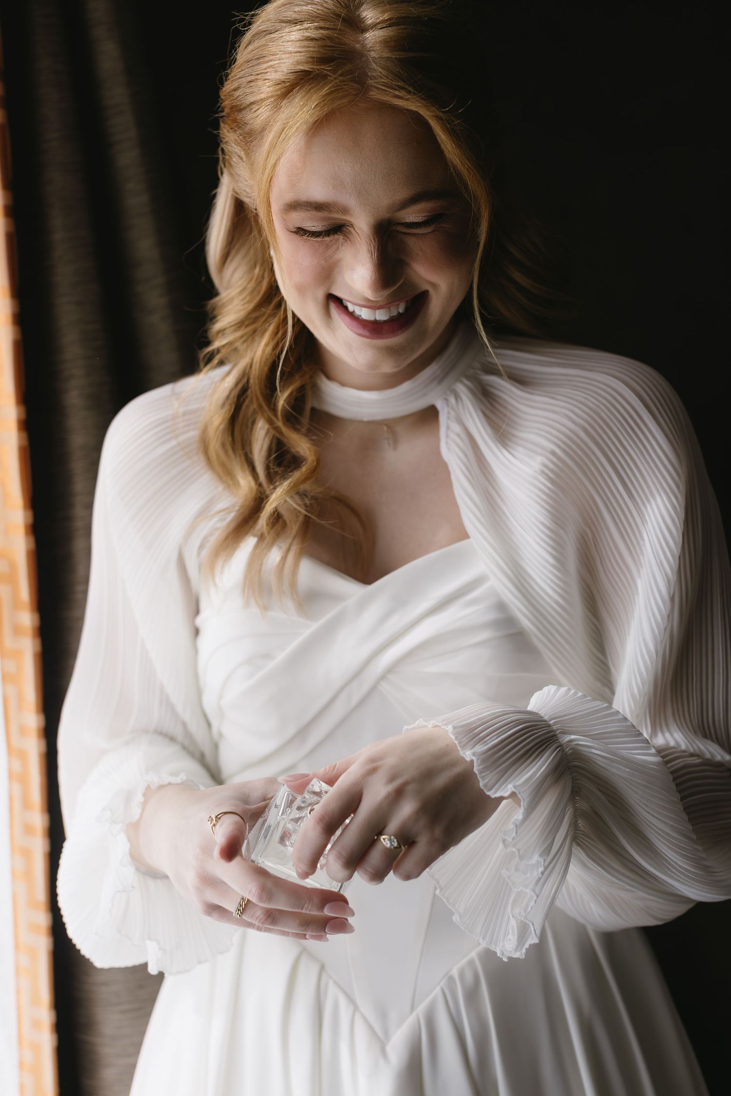 Candid shots of a bride in white dress smiling and looking down during wedding preparations.