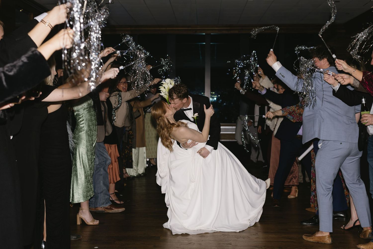 Wedding guests dance and celebrate on a dark dance floor.