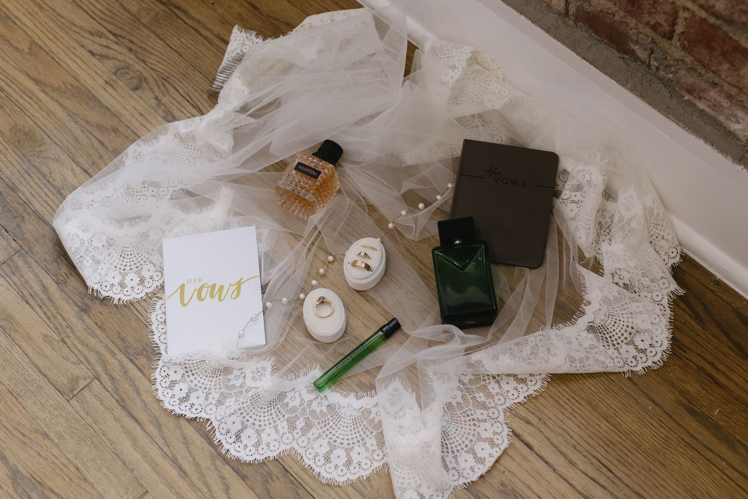 White lace wedding veil lies elegantly arranged on wooden floor next to small decorative accessories.
