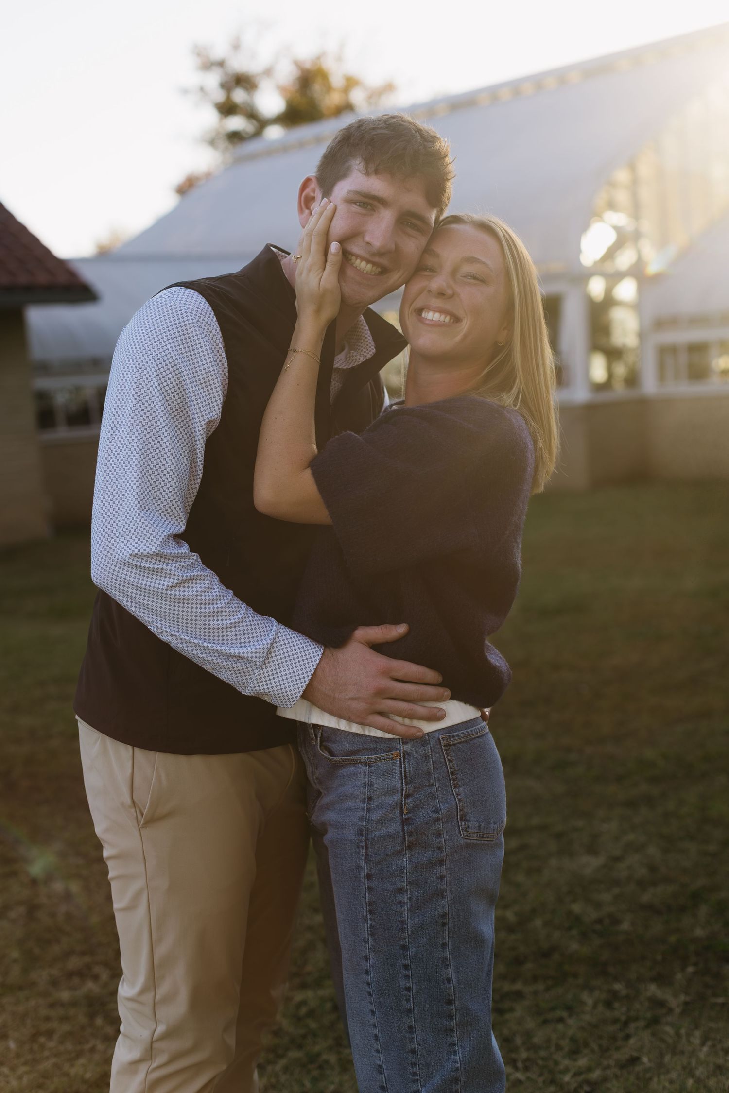 A tender moment between two people standing on grass during golden hour.