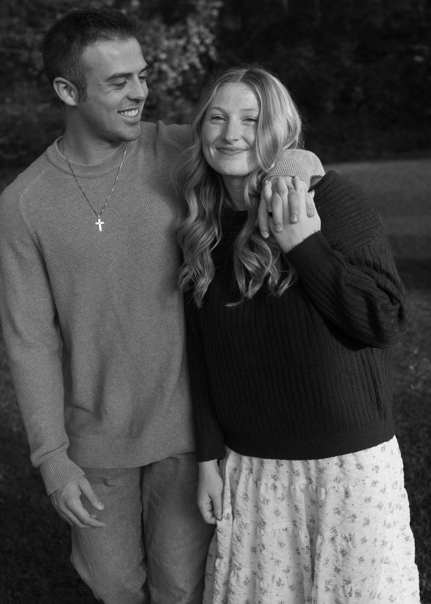A romantic couple shares an intimate moment outdoors while wearing casual fall attire.