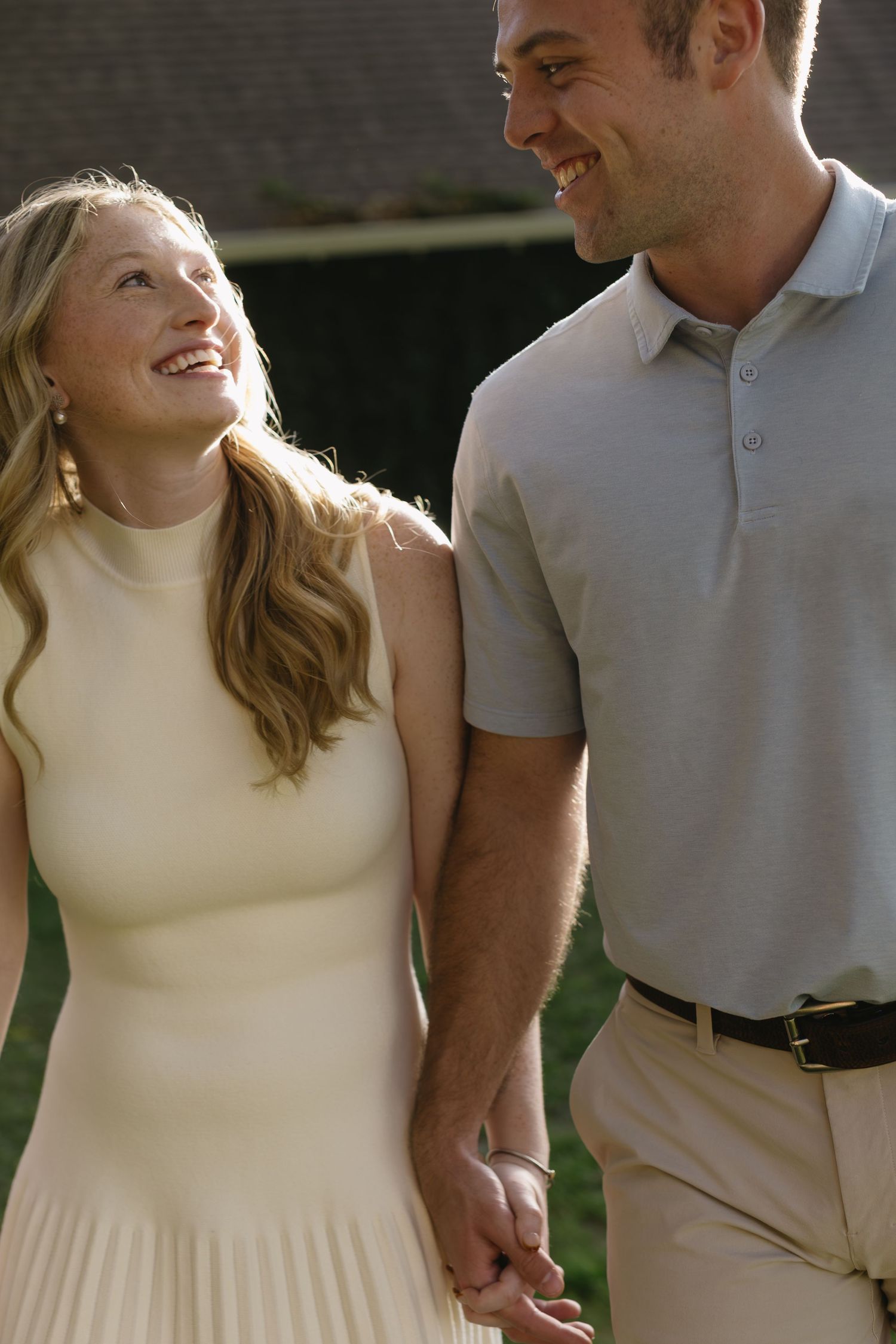 A couple in coordinating cream and grey outfits shares an intimate moment outdoors.