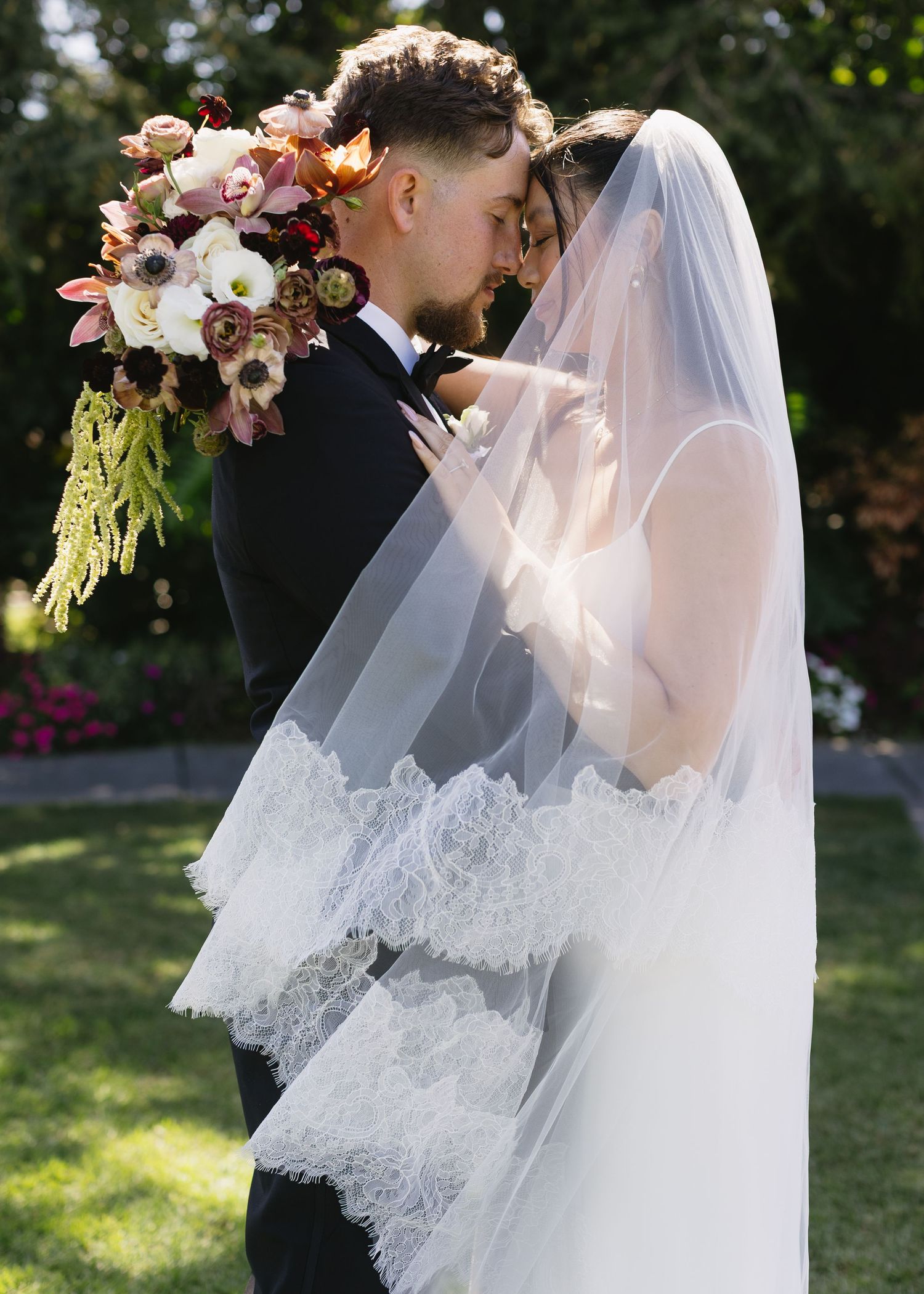 Romantic wedding moment captured in a garden setting with delicate floral bouquet.