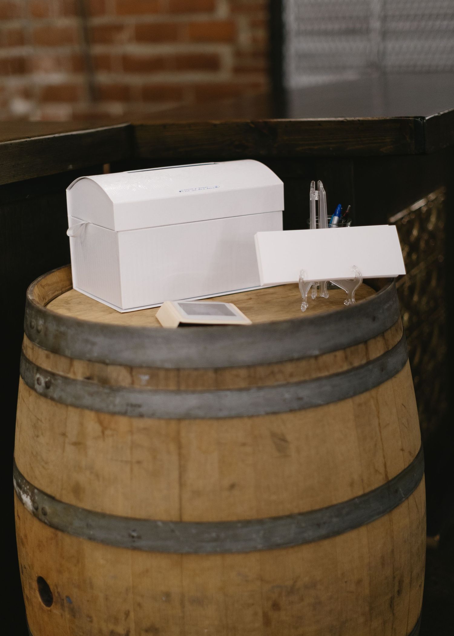 White box and supplies arranged on a rustic wooden barrel in an industrial setting.