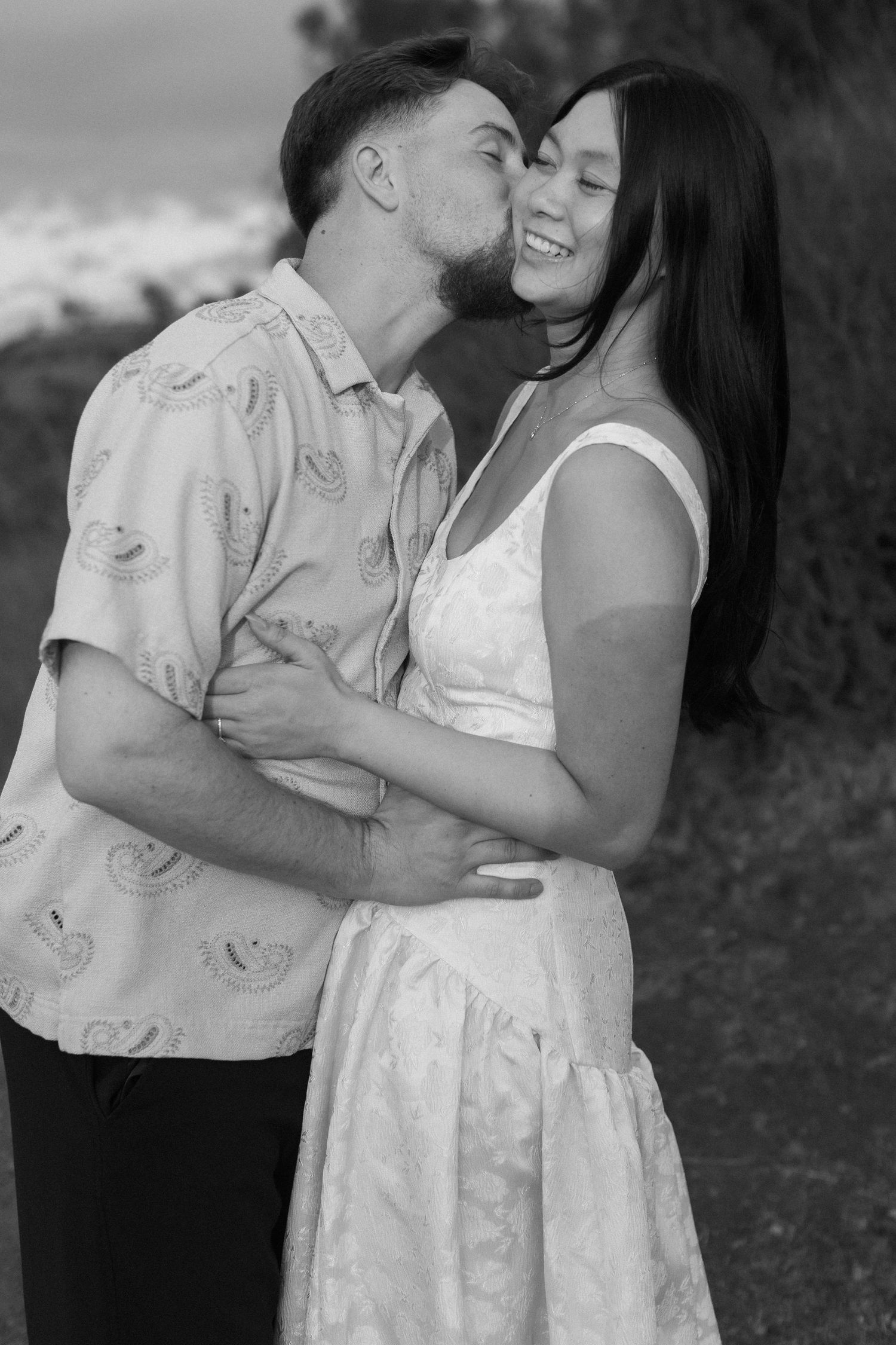 Intimate black and white portrait of couple embracing outdoors.