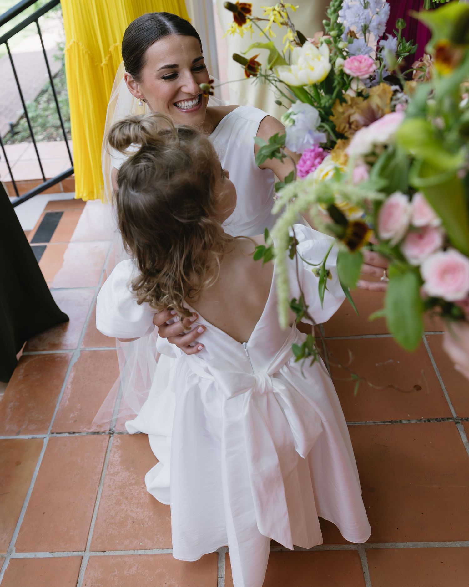 Garden wedding scene features fresh floral arrangements with pink and white blooms against a yellow backdrop.