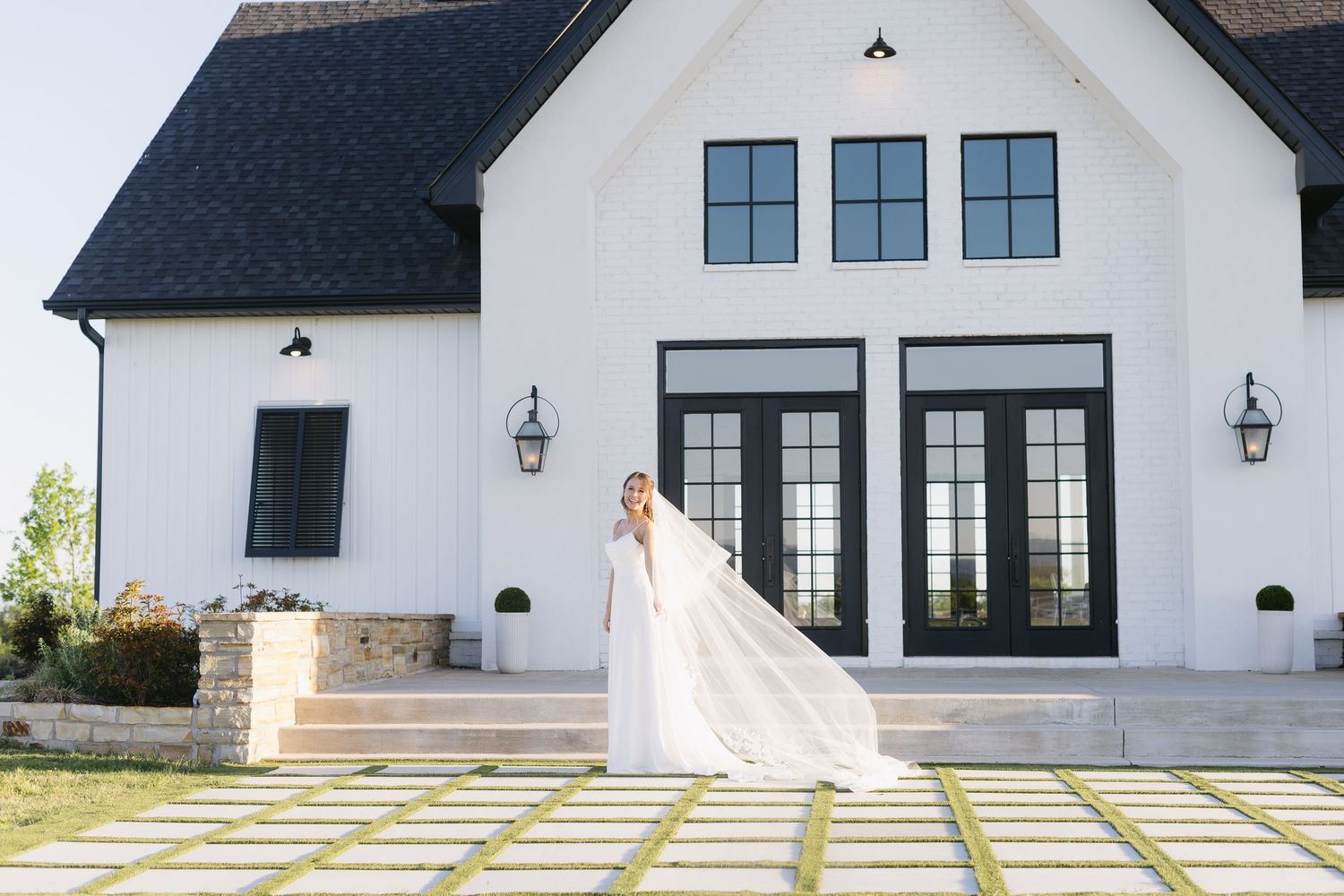 Exterior view of a modern farmhouse-style wedding venue with white walls and black trim.