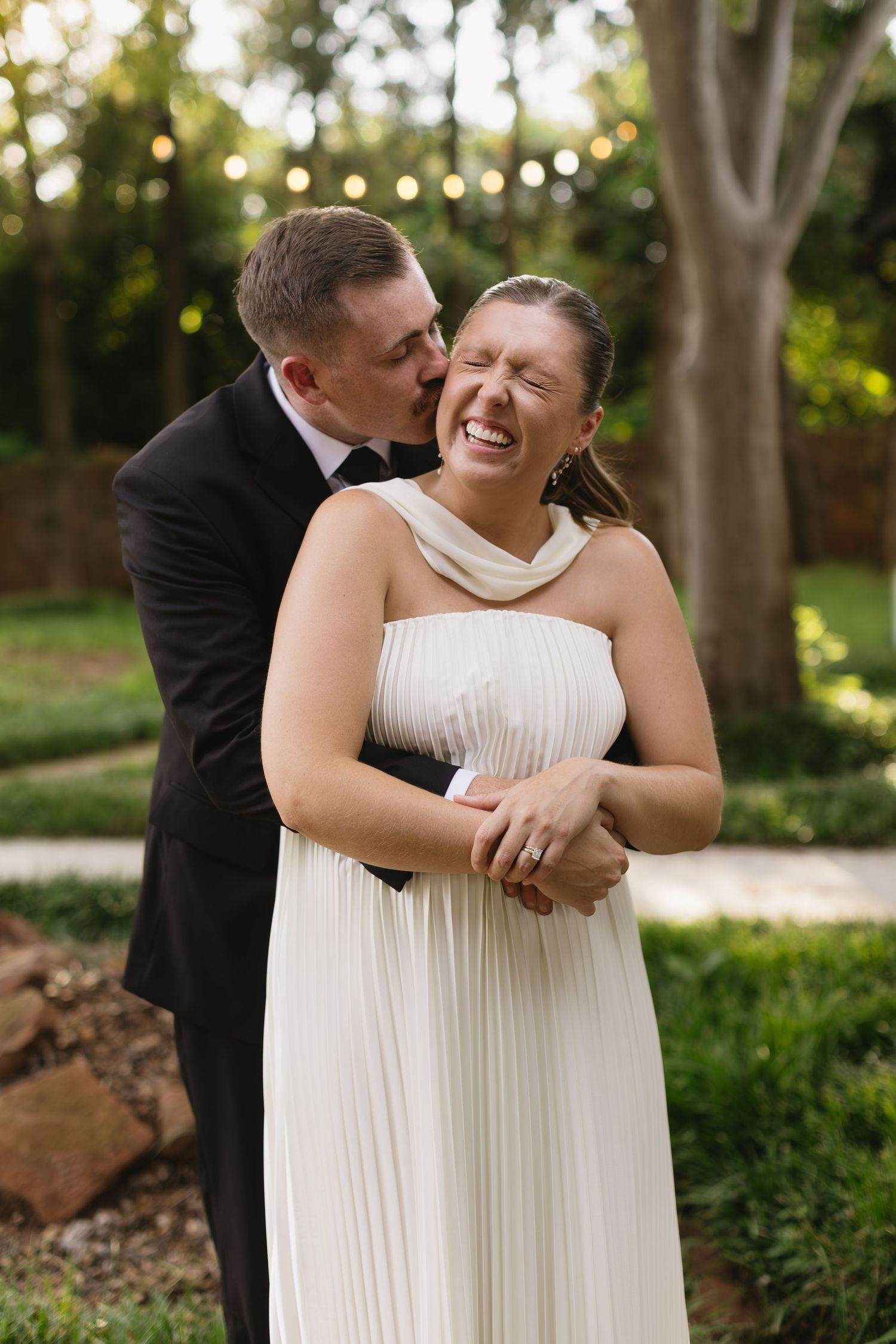 A joyful moment between newlyweds in a garden with string lights.