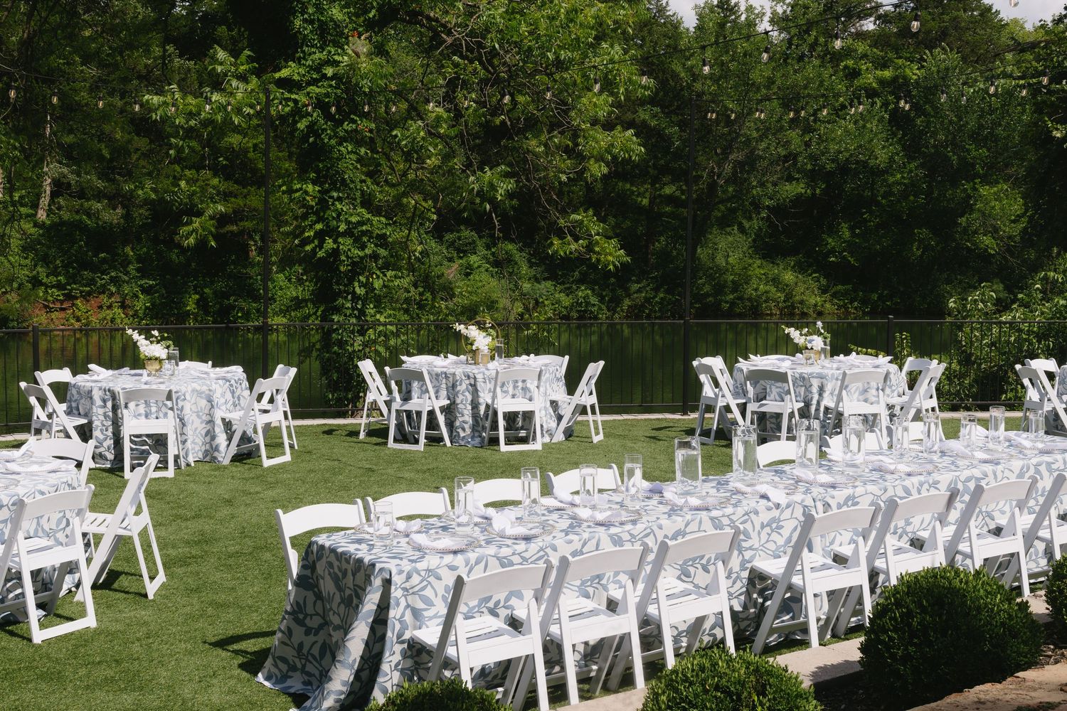 Outdoor wedding ceremony setup with rows of white chairs on a green lawn.