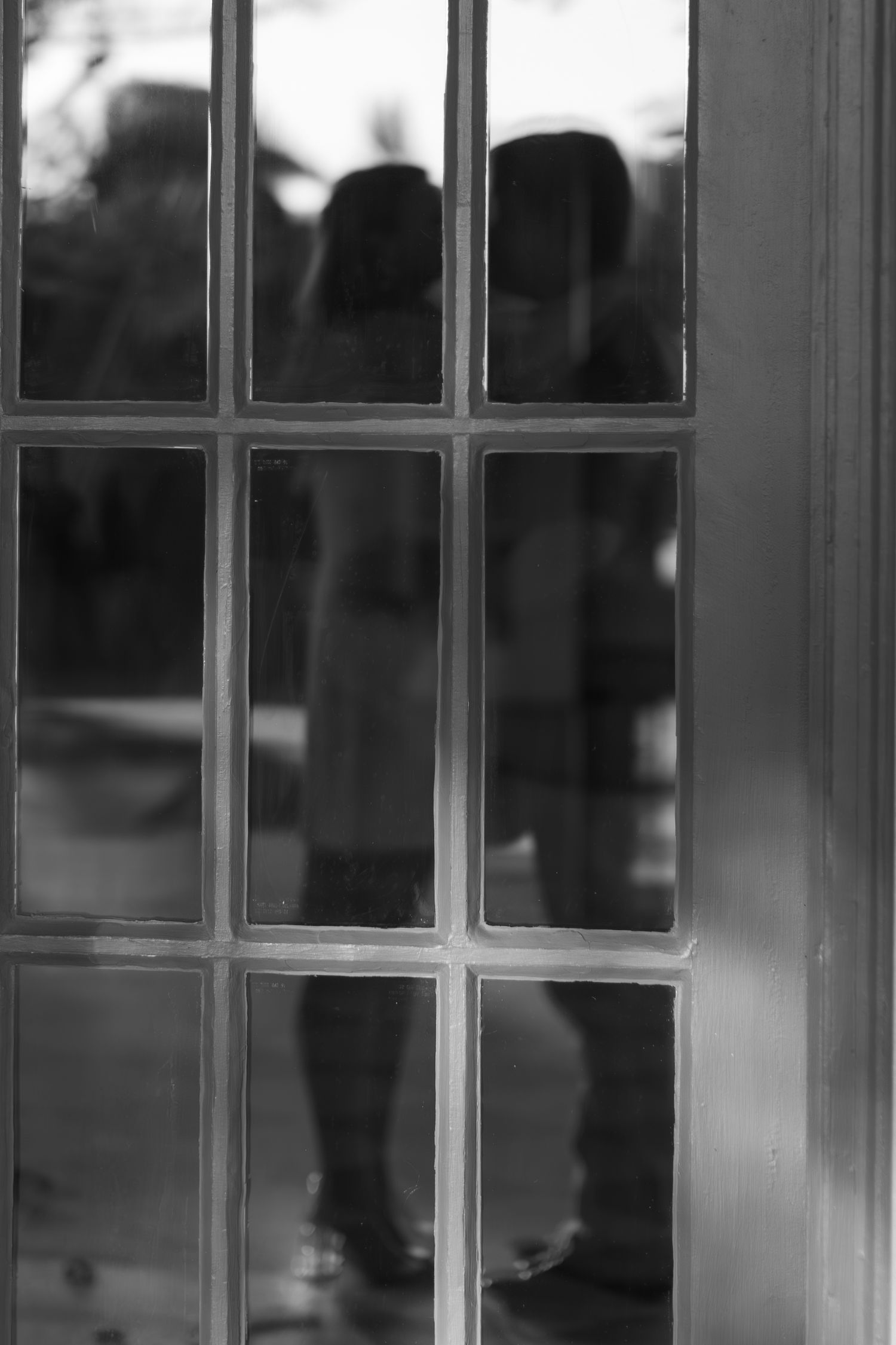 A row of classic white French doors with glass panes letting in natural light against a soft blurred background.