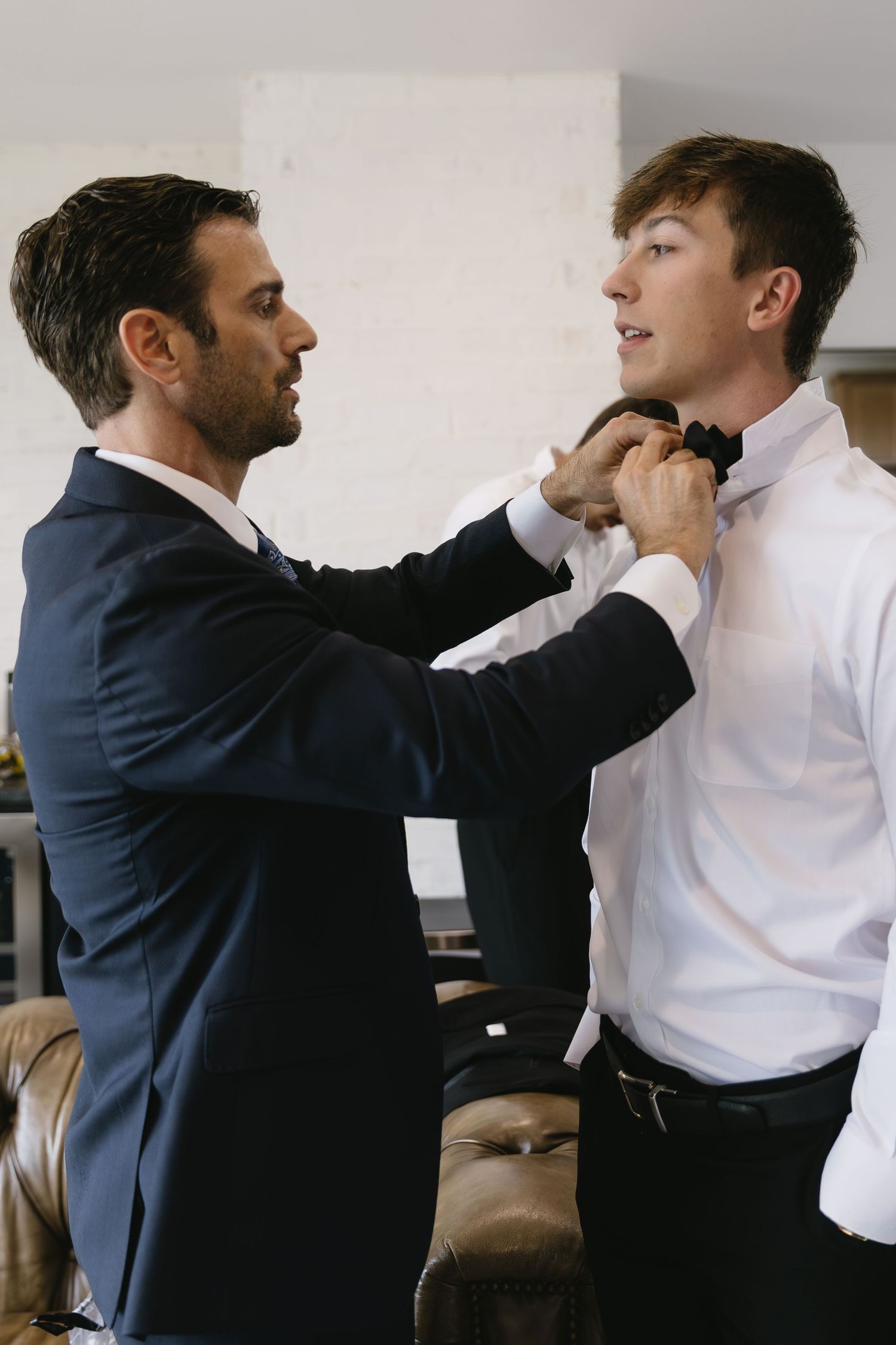 Sequence showing a groomsman helping another adjust his tie before a wedding.