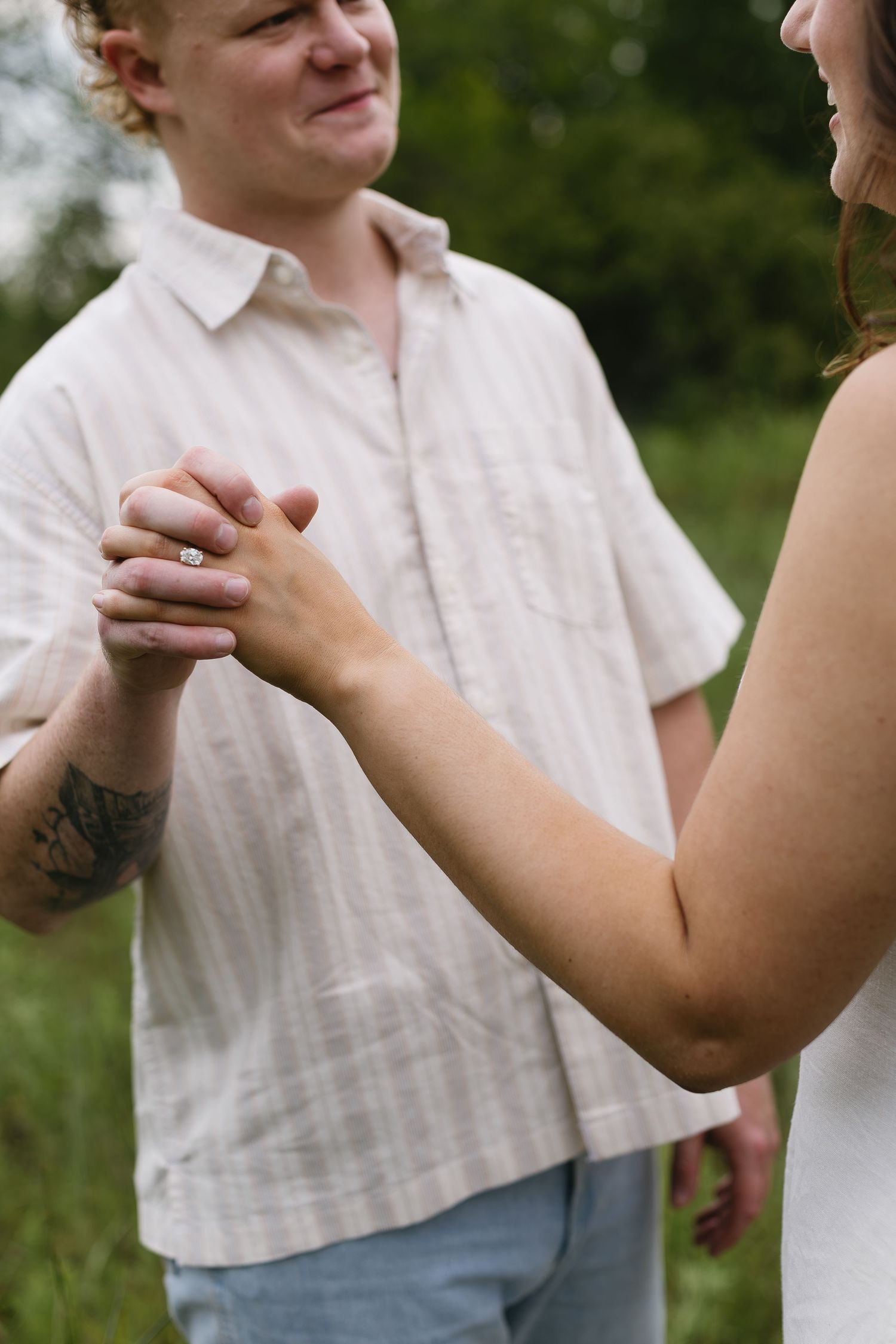 Close-up of hands clasped together during an intimate outdoor photoshoot.