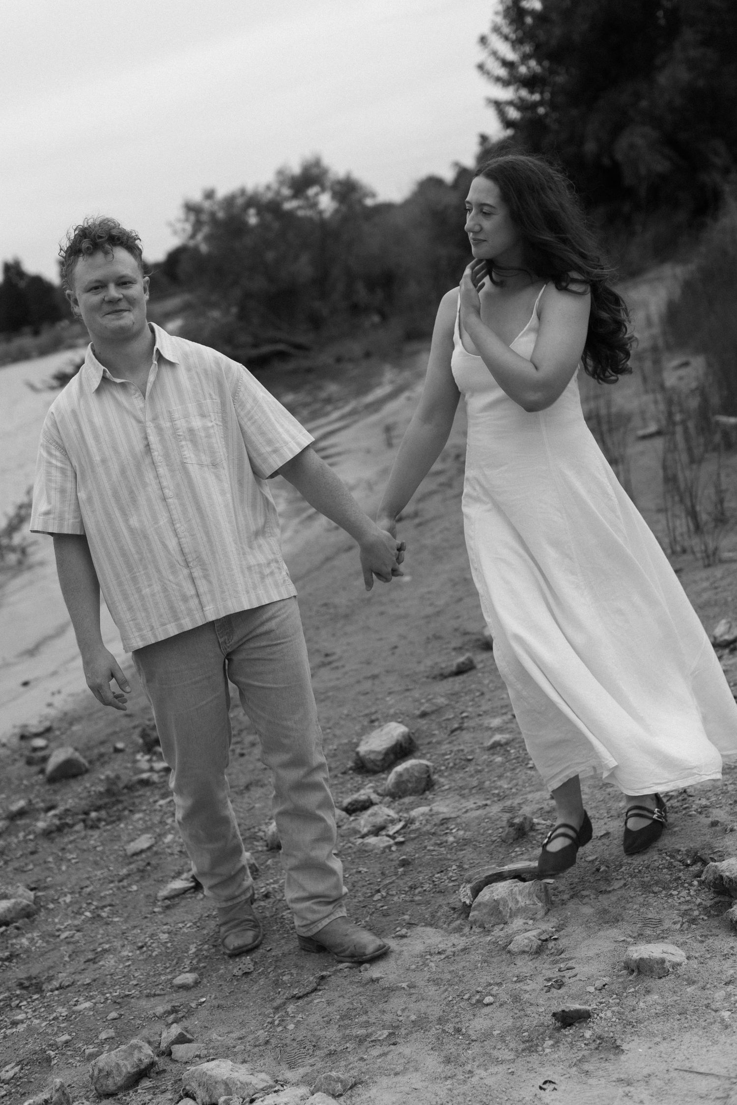 Black and white series capturing candid moments of a couple walking and holding hands on rocky terrain.