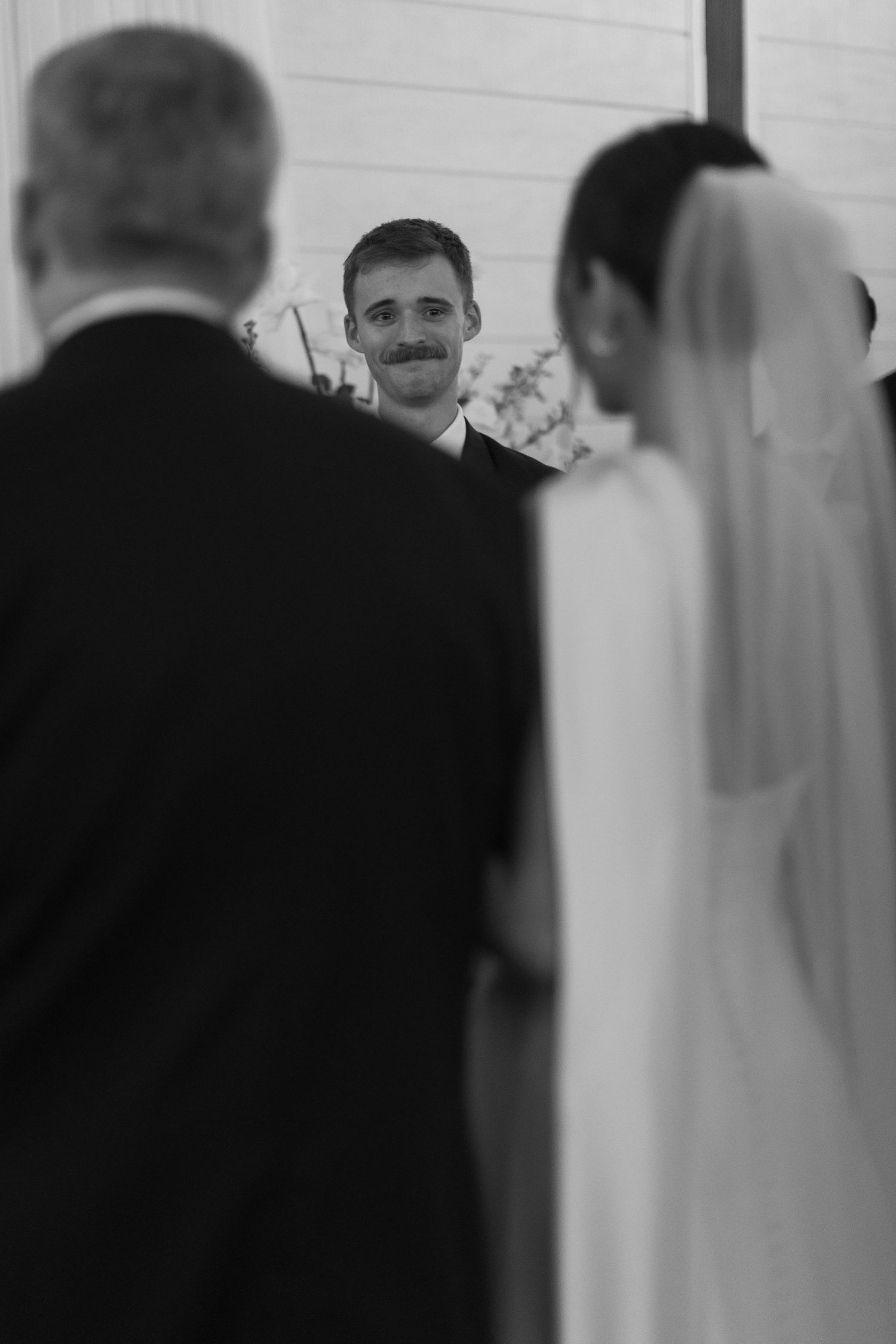Blurred black and white image showing silhouettes in an indoor wedding venue.