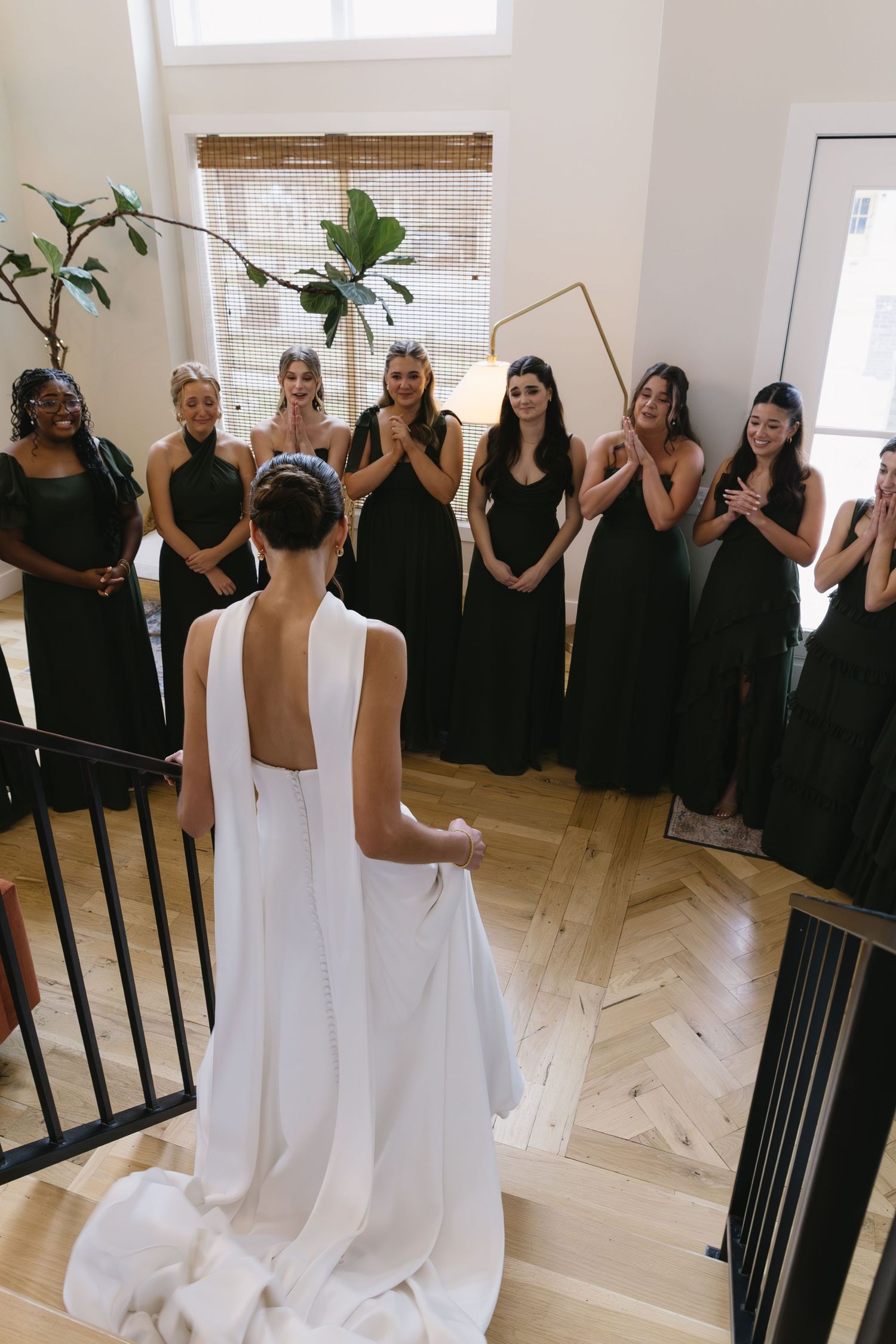 Wedding party members in black dresses watch as bride in white reads a message.