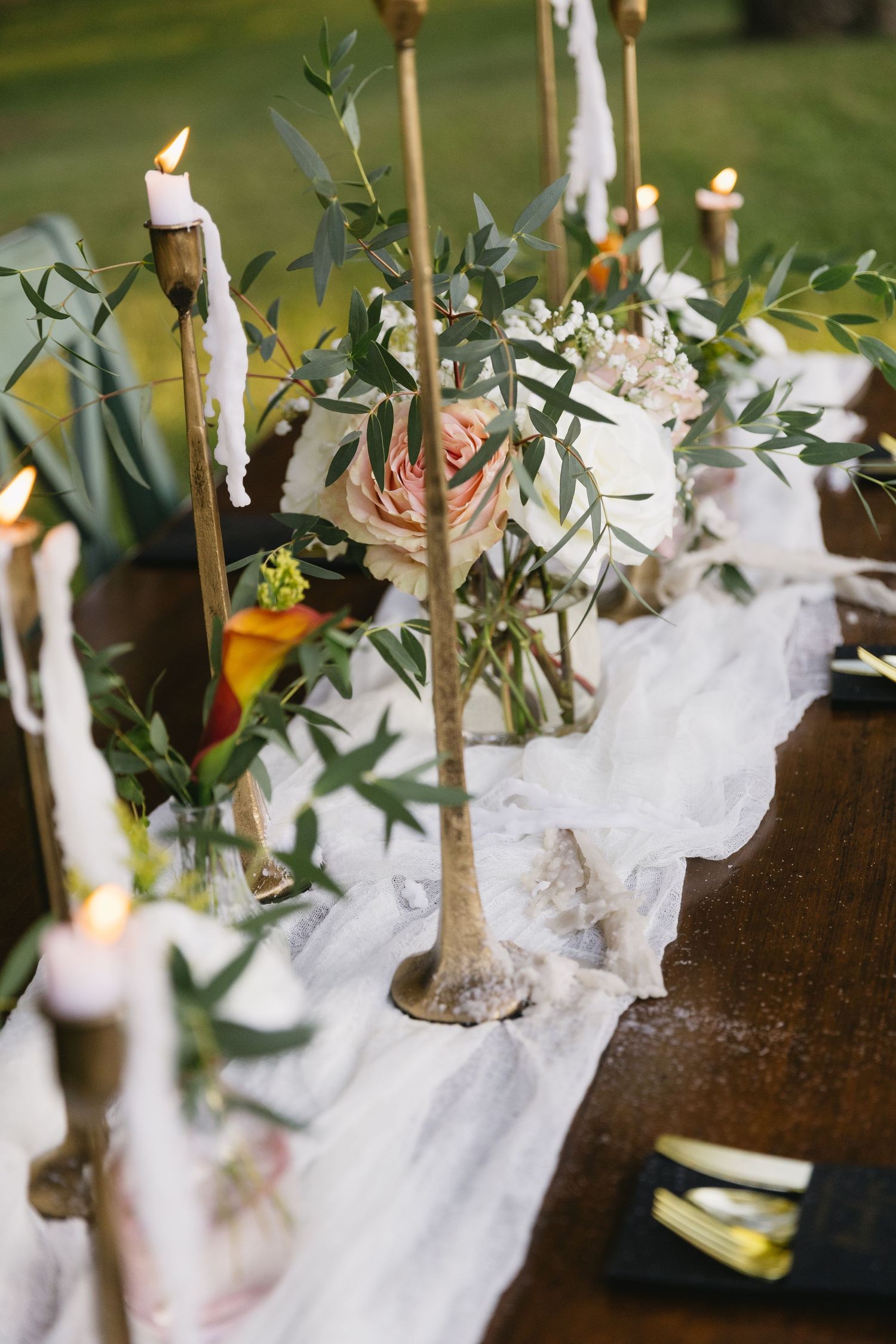 White fabric and greenery decorate rustic wooden tables with tealight candles for a wedding reception.