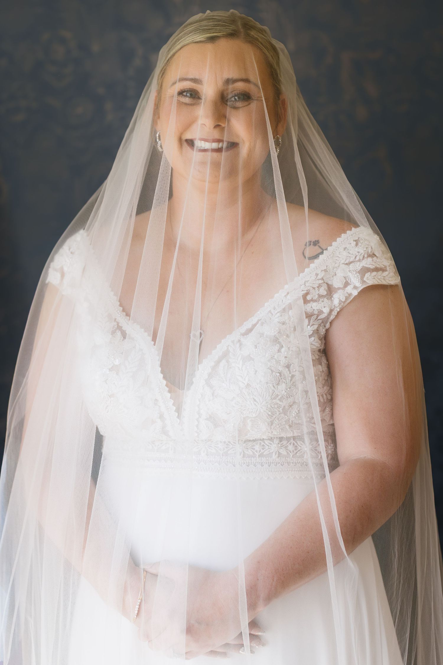 Romantic bridal portrait featuring a flowing veil and delicate lace V-neck wedding dress.