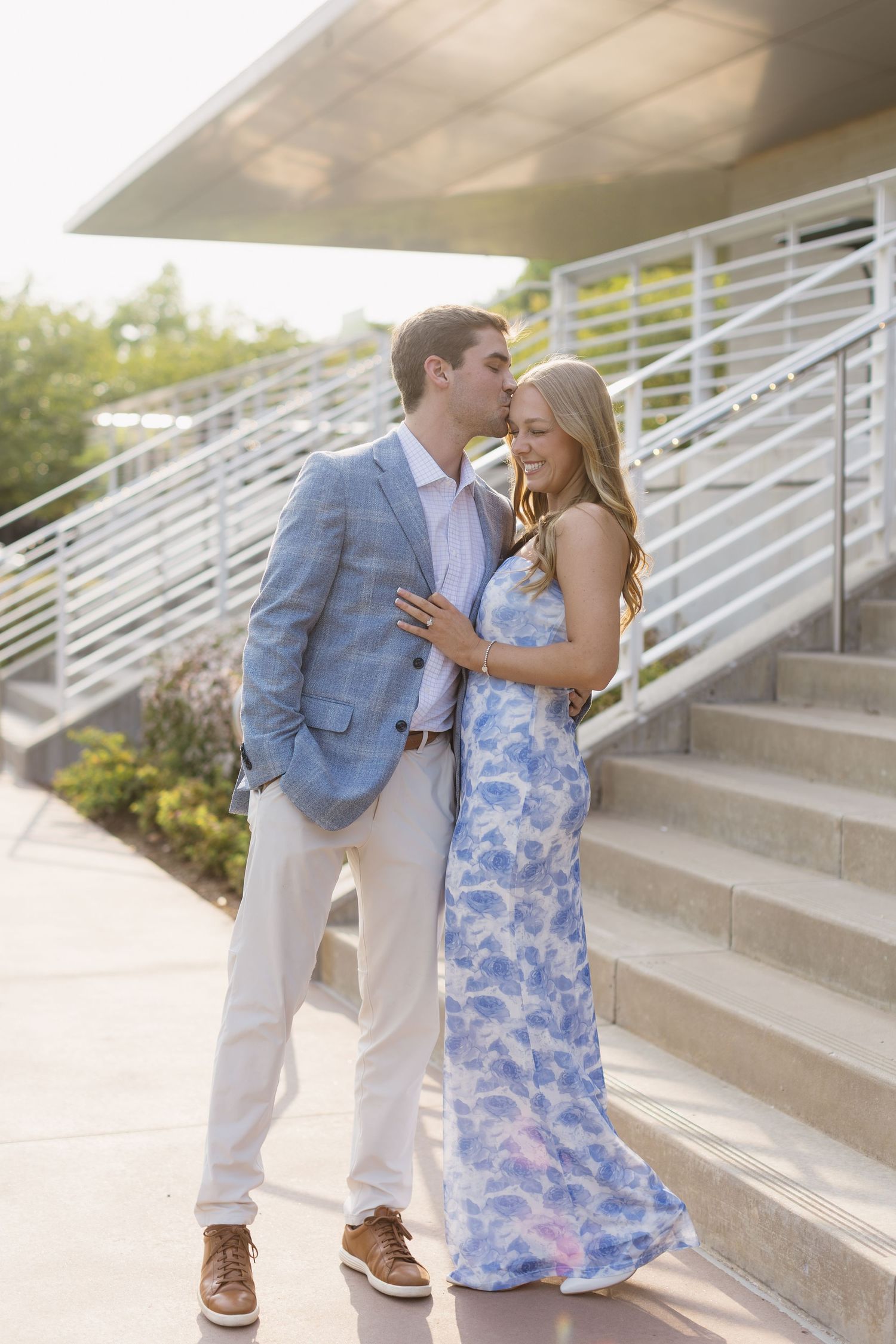 Couple in coordinating blue and grey outfits embracing on outdoor concrete steps.