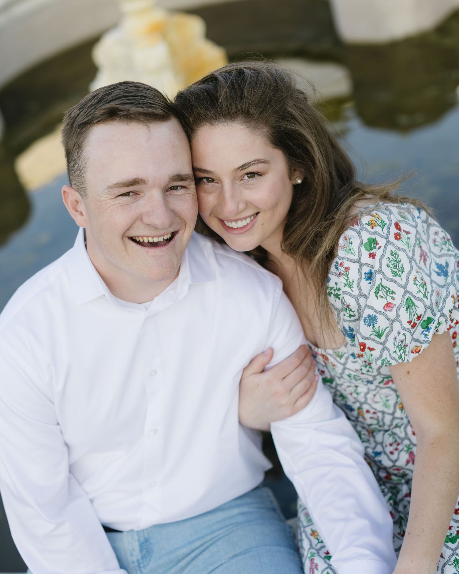 A couple shares joyful laughter while posing together for casual outdoor portraits.