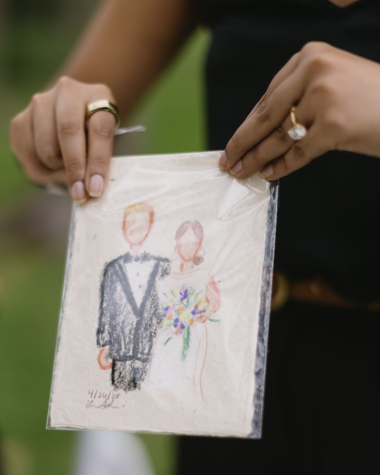 Hands holding a wedding-themed watercolor illustration on white paper.