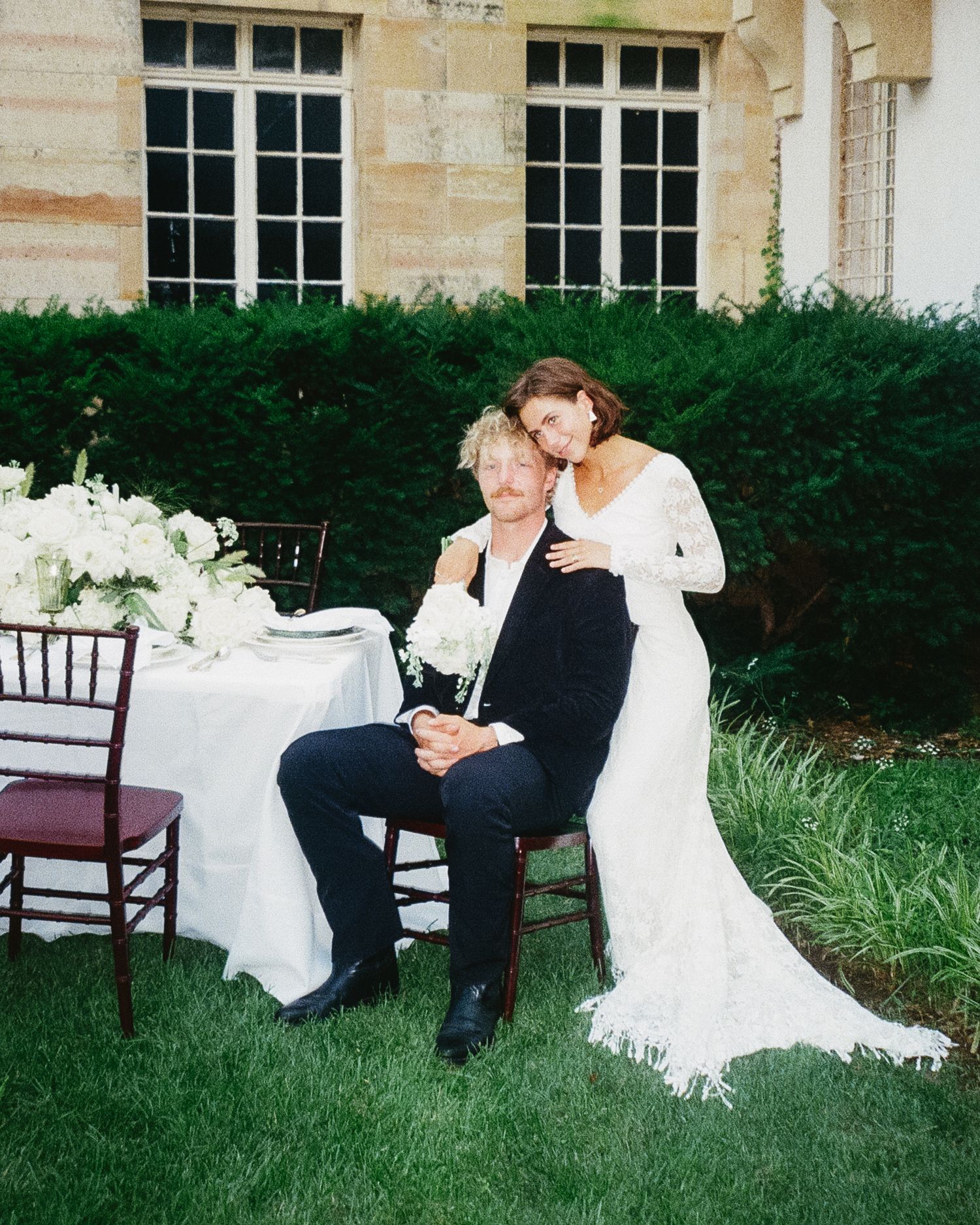 A romantic outdoor wedding moment captured next to an elegant table setting with white flowers.