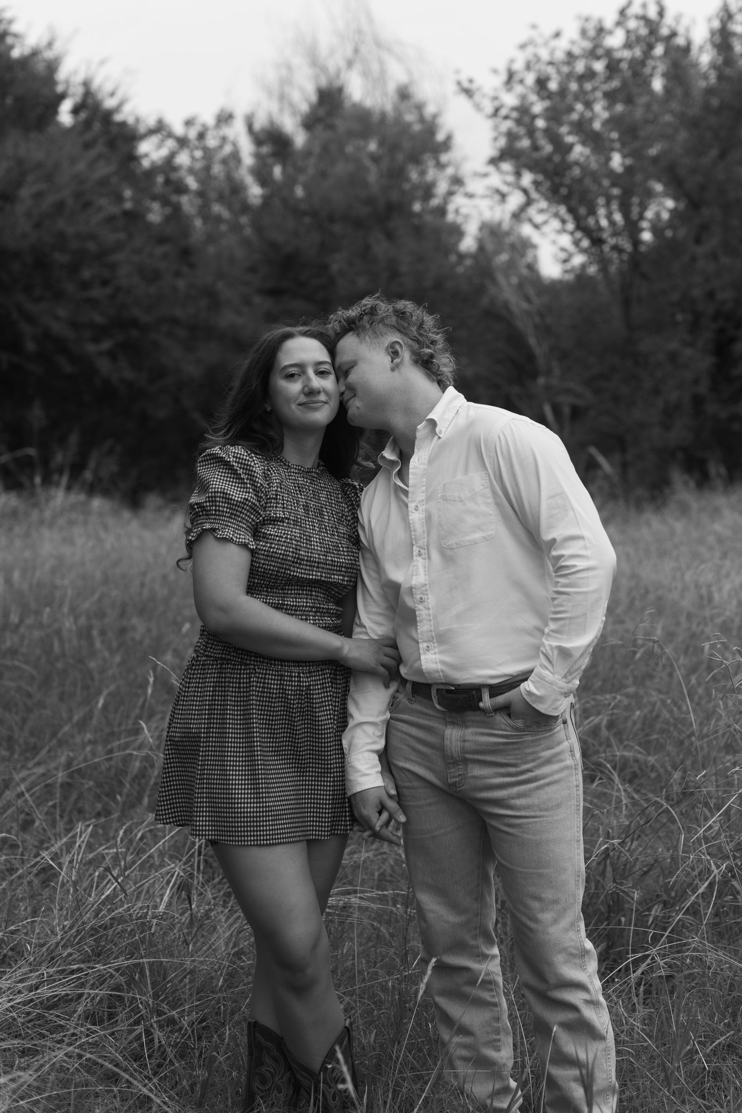 A black and white photo series of a couple sharing intimate moments in tall grass.
