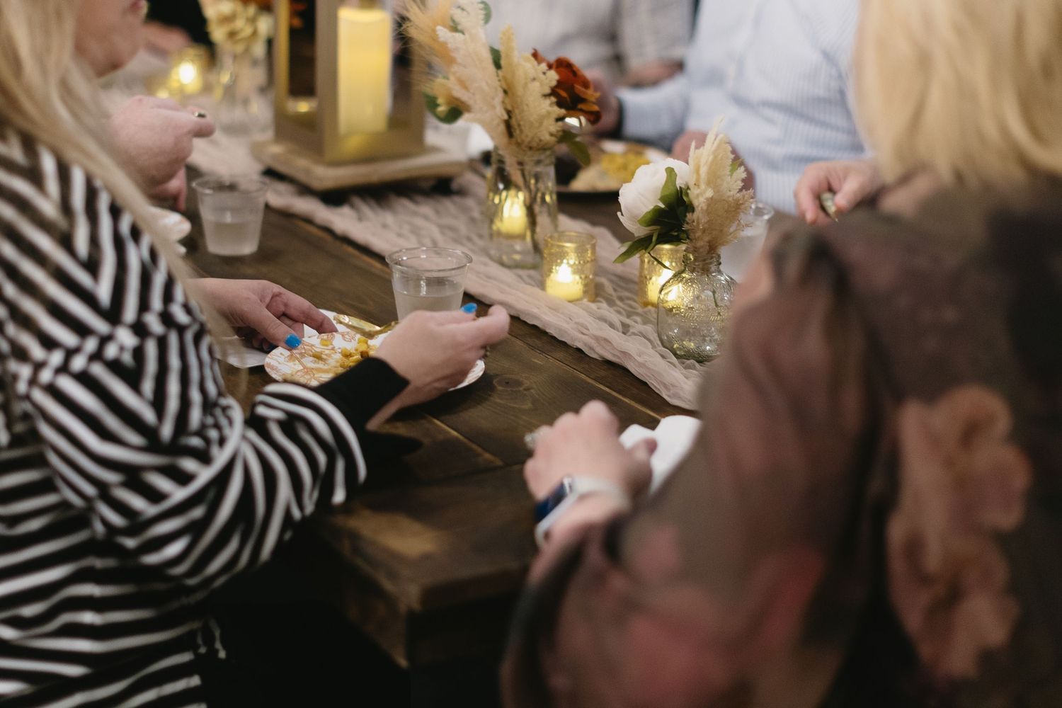 Intimate gathering around a rustic table with striped patterns and candlelight.