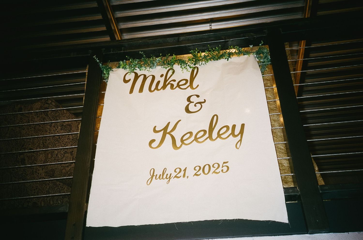 Wedding signage with elegant gold script lettering displayed at a venue.