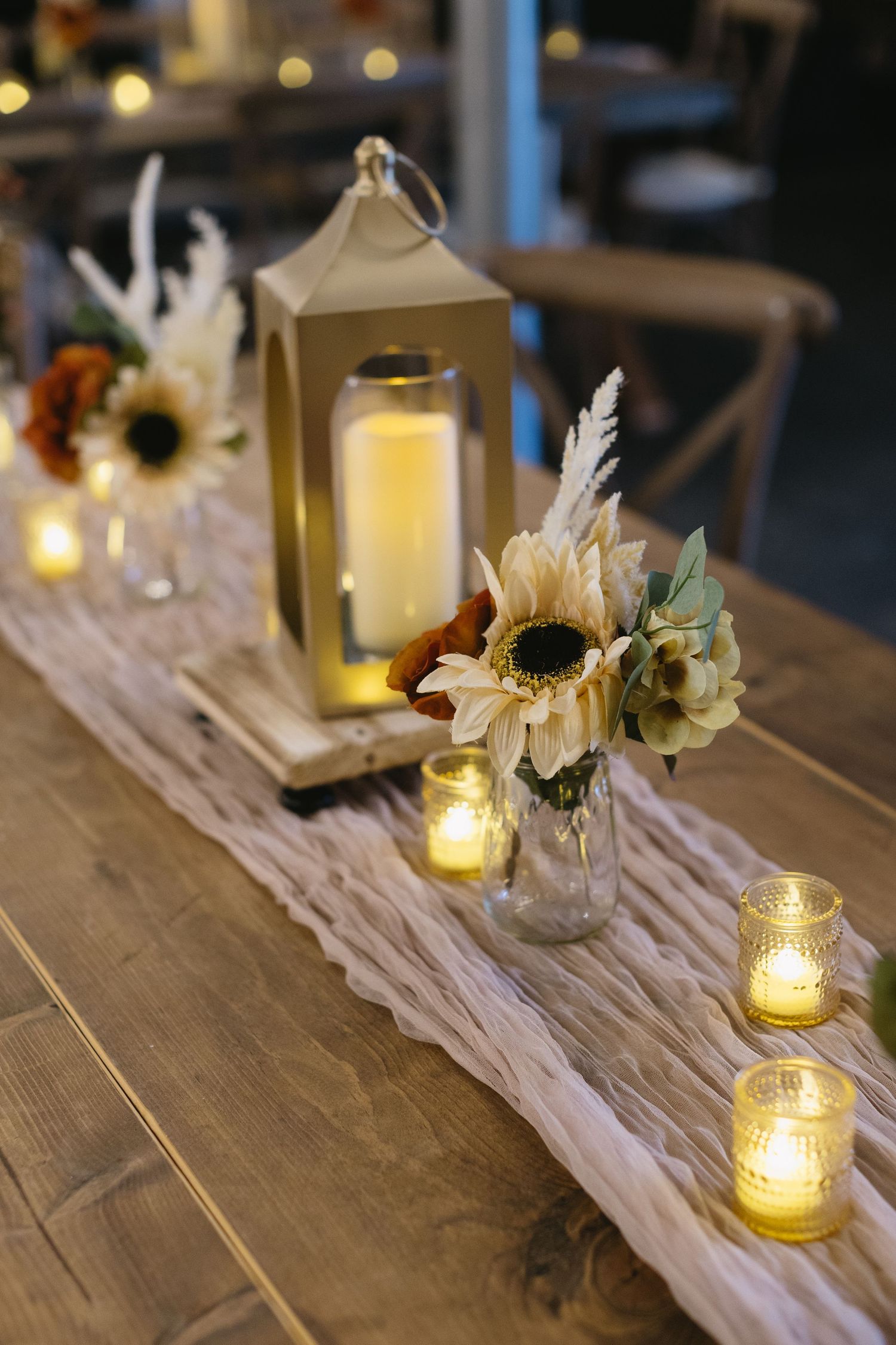 Rustic wooden table decorated with glowing candles and white floral centerpieces for a wedding reception.