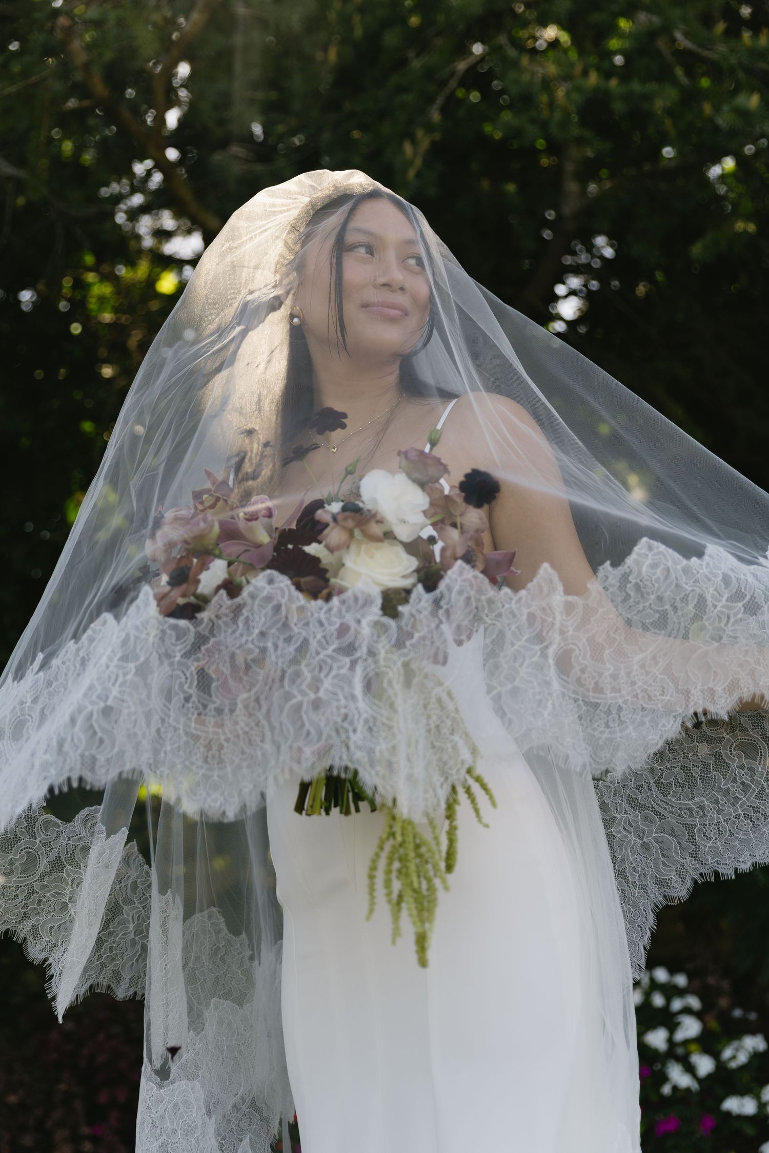 Ethereal bridal portraits with lace veil and romantic floral bouquet in natural light.