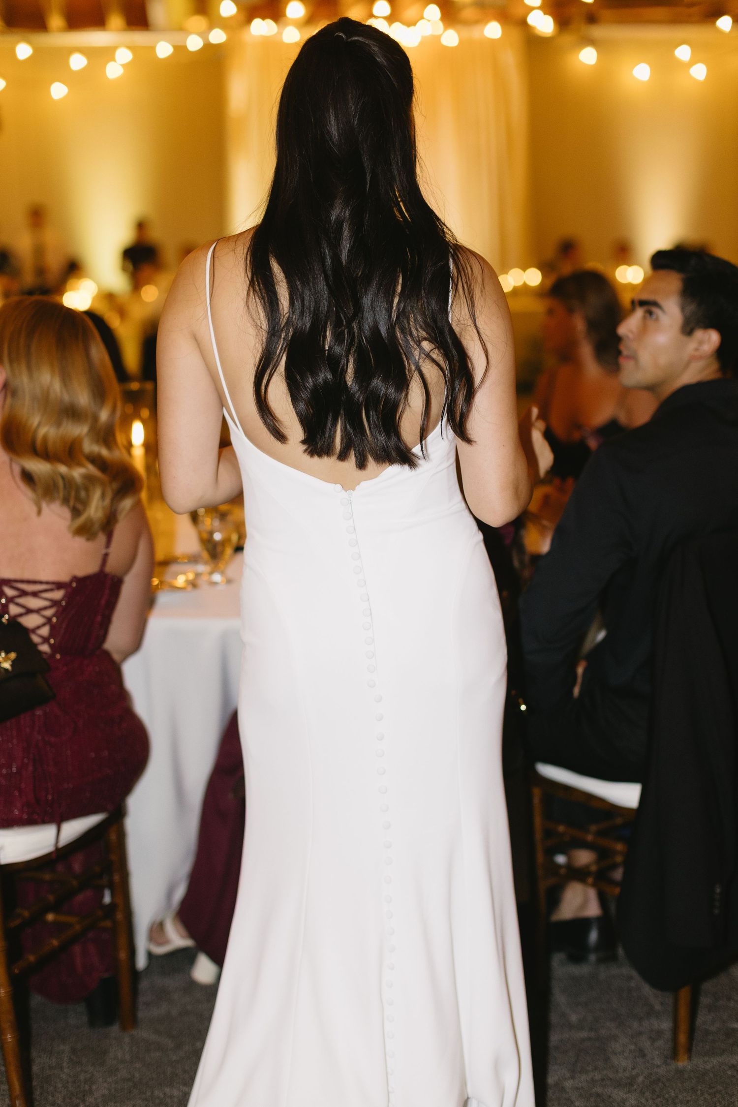 Wedding reception venue with guests mingling under warm string lights.