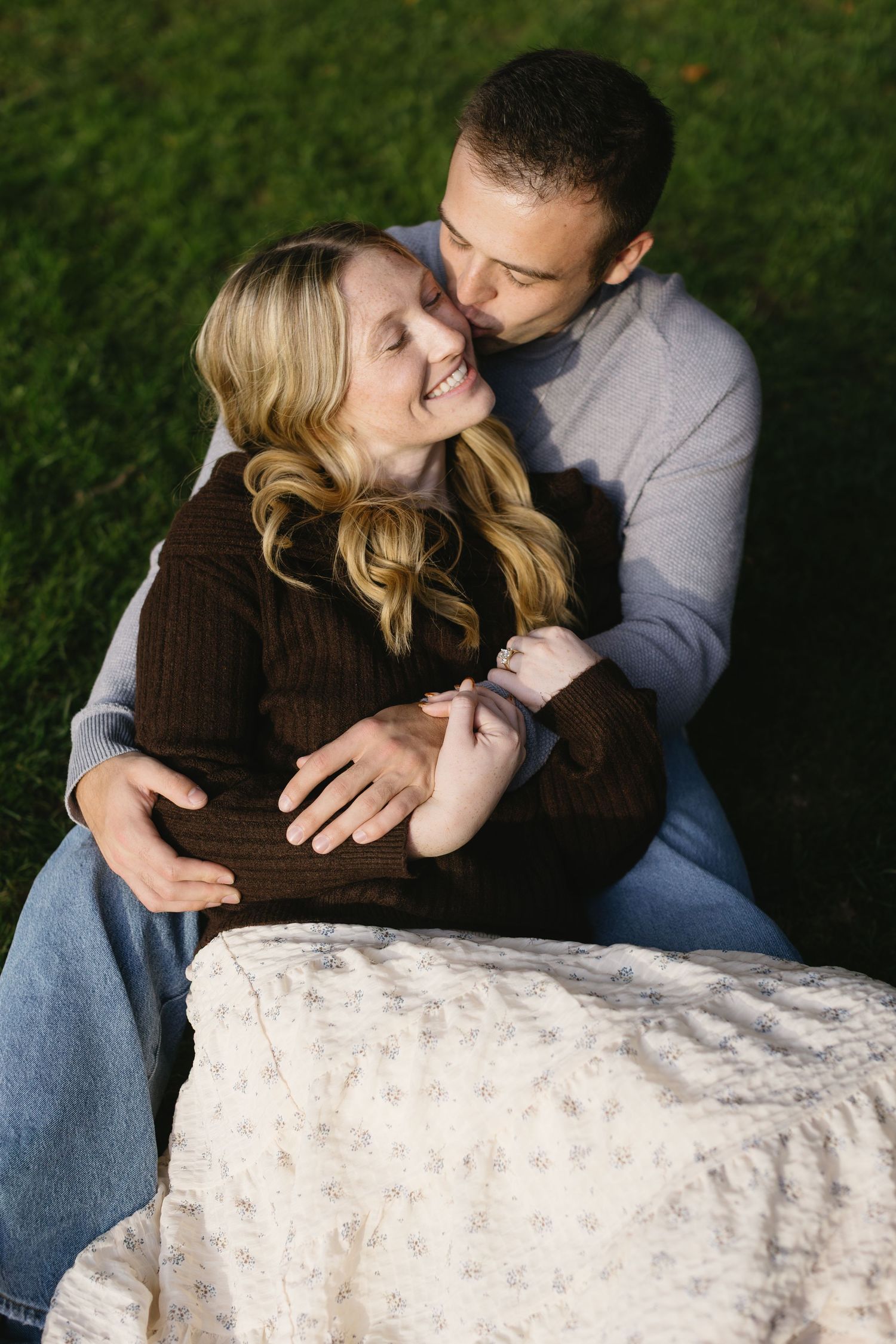 Couple sharing intimate moments while sitting on stone wall outdoors.