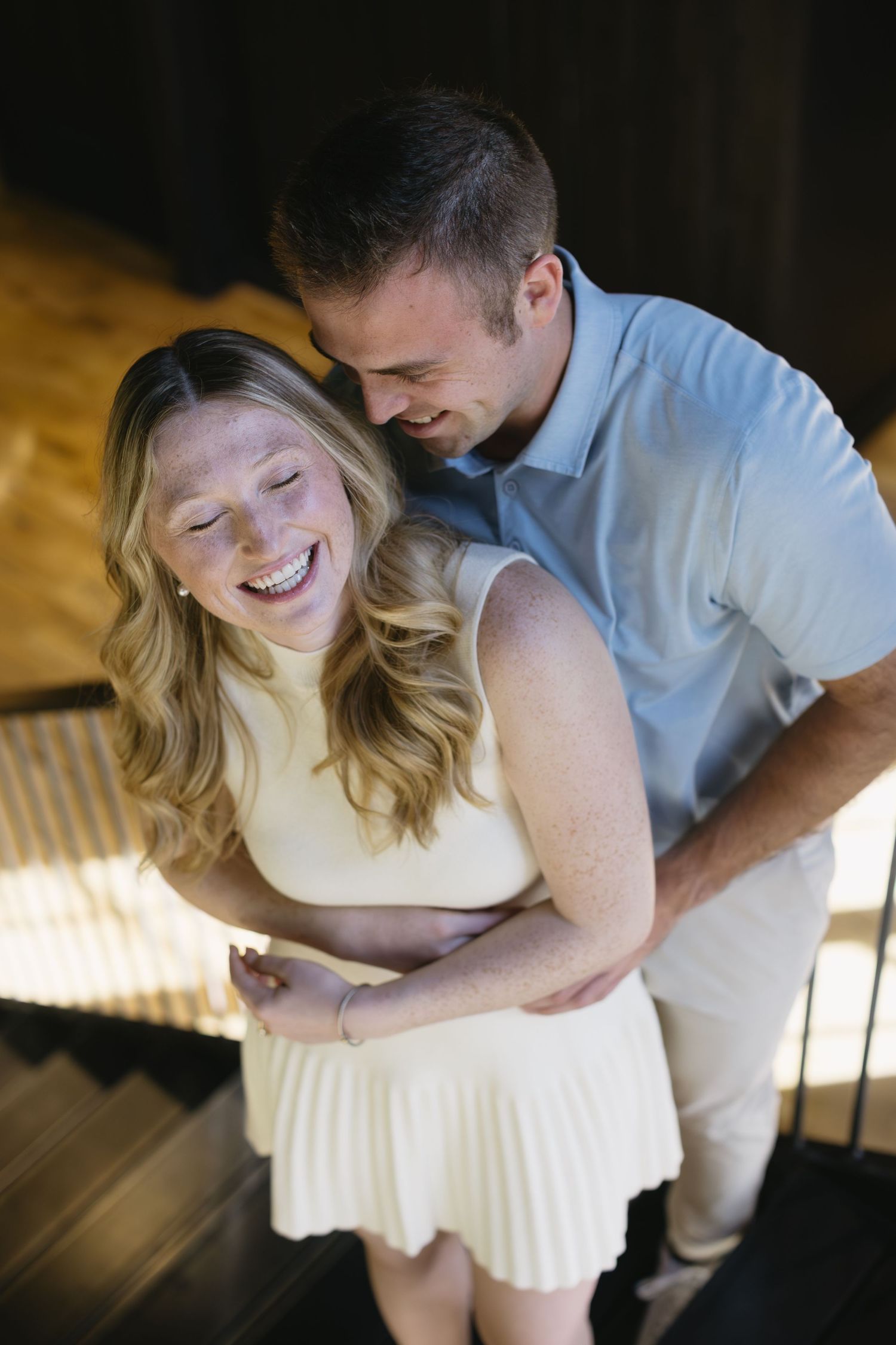 A romantic indoor photoshoot with a couple sharing intimate moments in soft lighting.