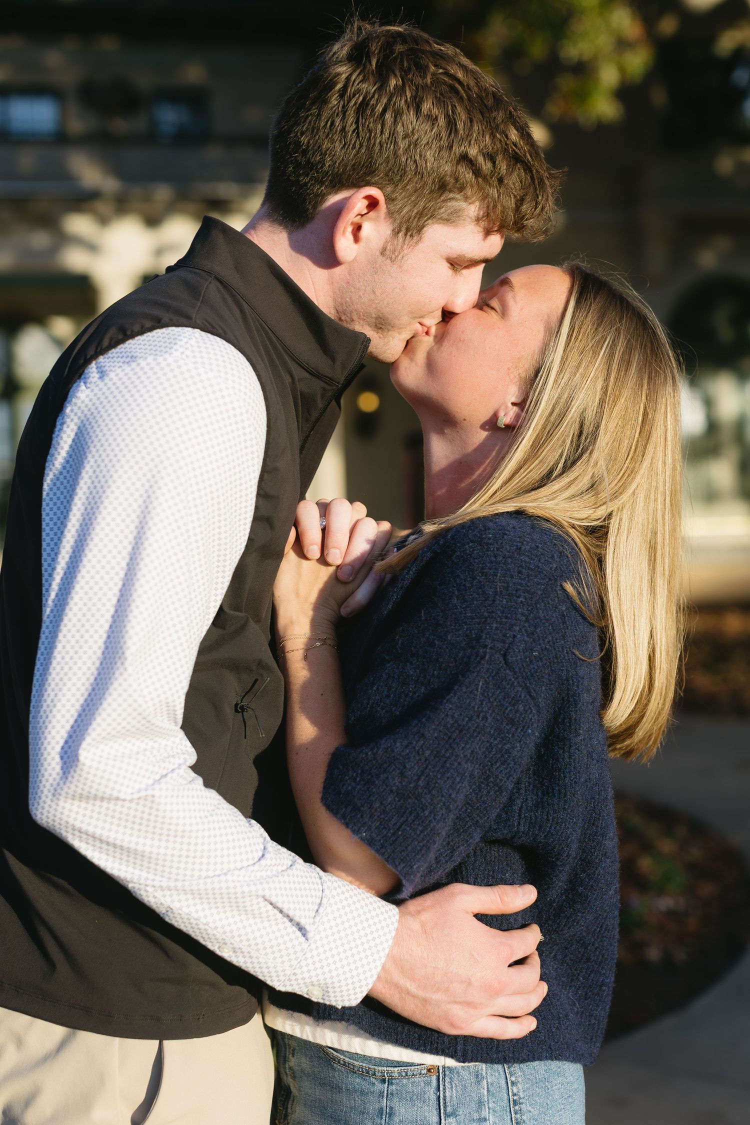 A romantic kiss shared between a couple in late afternoon sunlight.