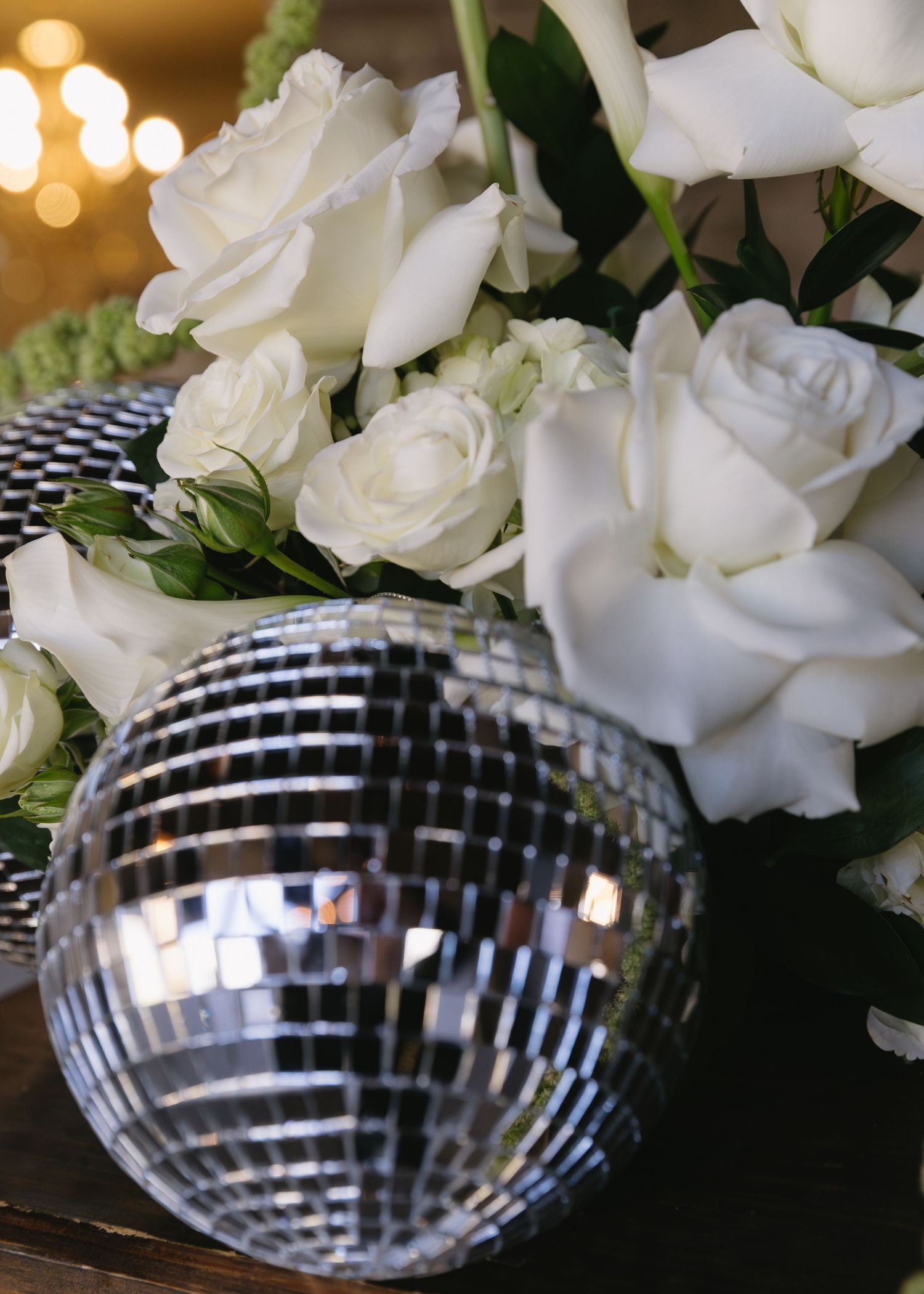 White roses and disco ball decorations create an elegant party atmosphere.