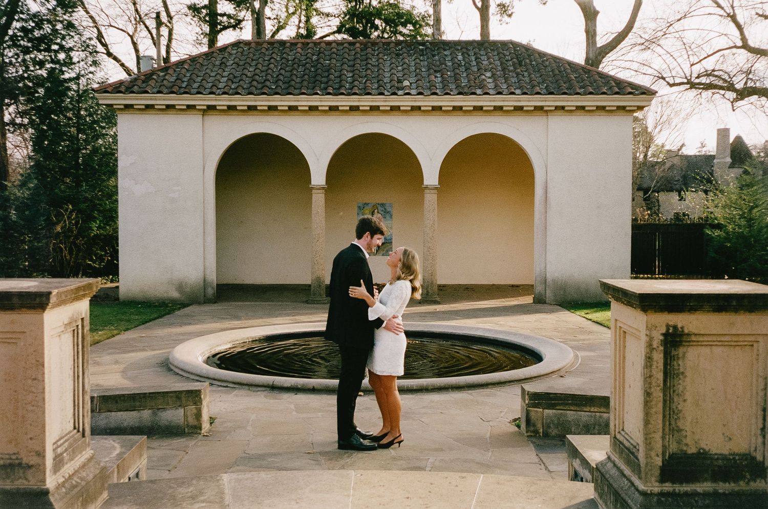 A romantic moment captured under Mediterranean-style arches at a historic venue.