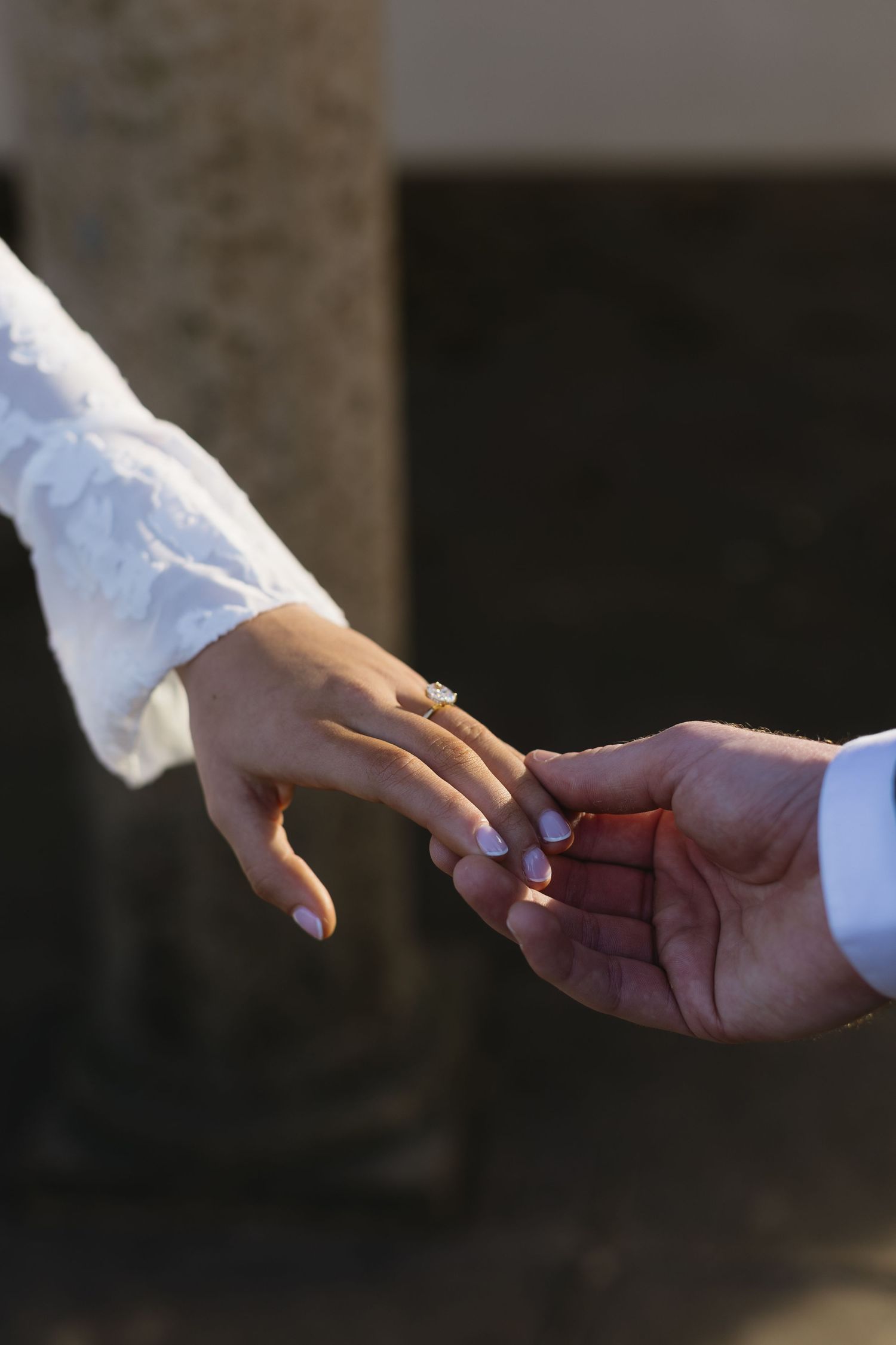 Close-up of hands exchanging a ring during a romantic proposal moment.