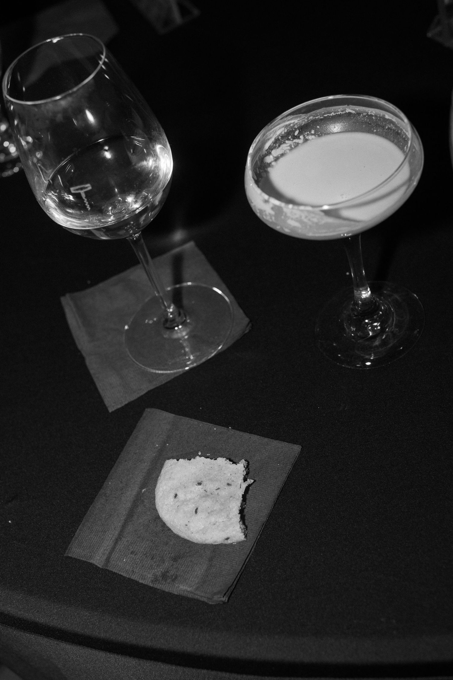 Empty wine glasses and small plates on a dark table surface.