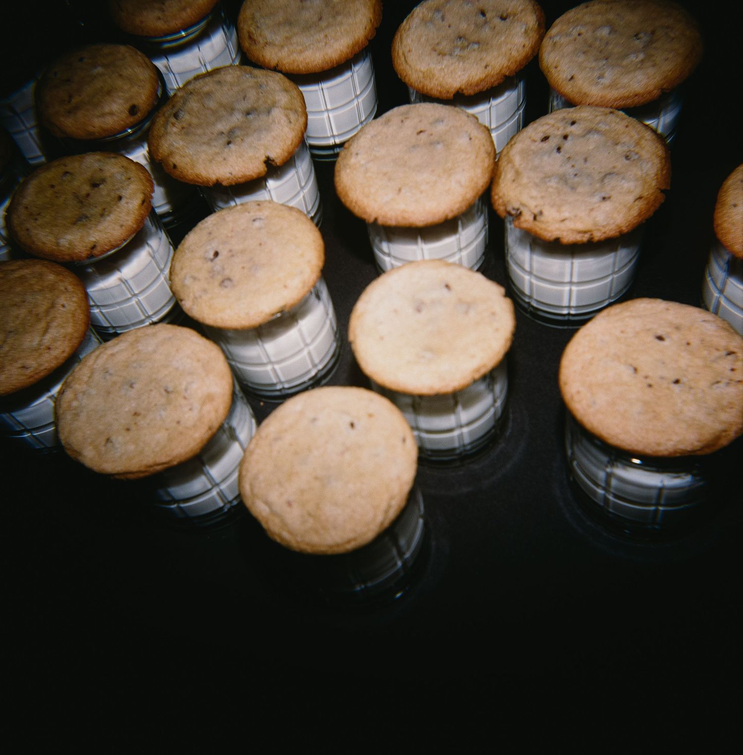 Rows of chocolate chip cookies displayed on dark background.