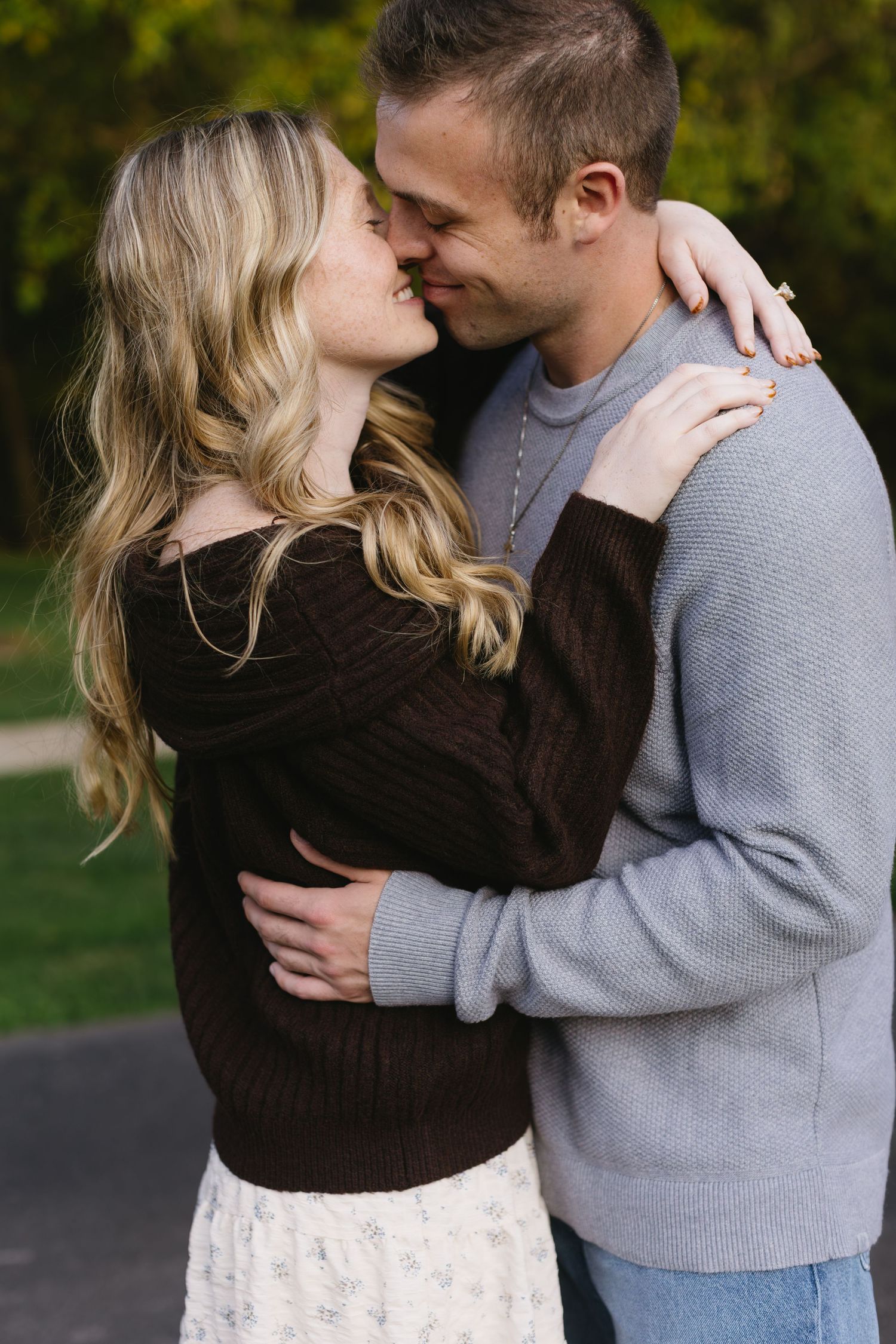 Couple in sweaters embracing and sharing tender moments during an outdoor photo session.