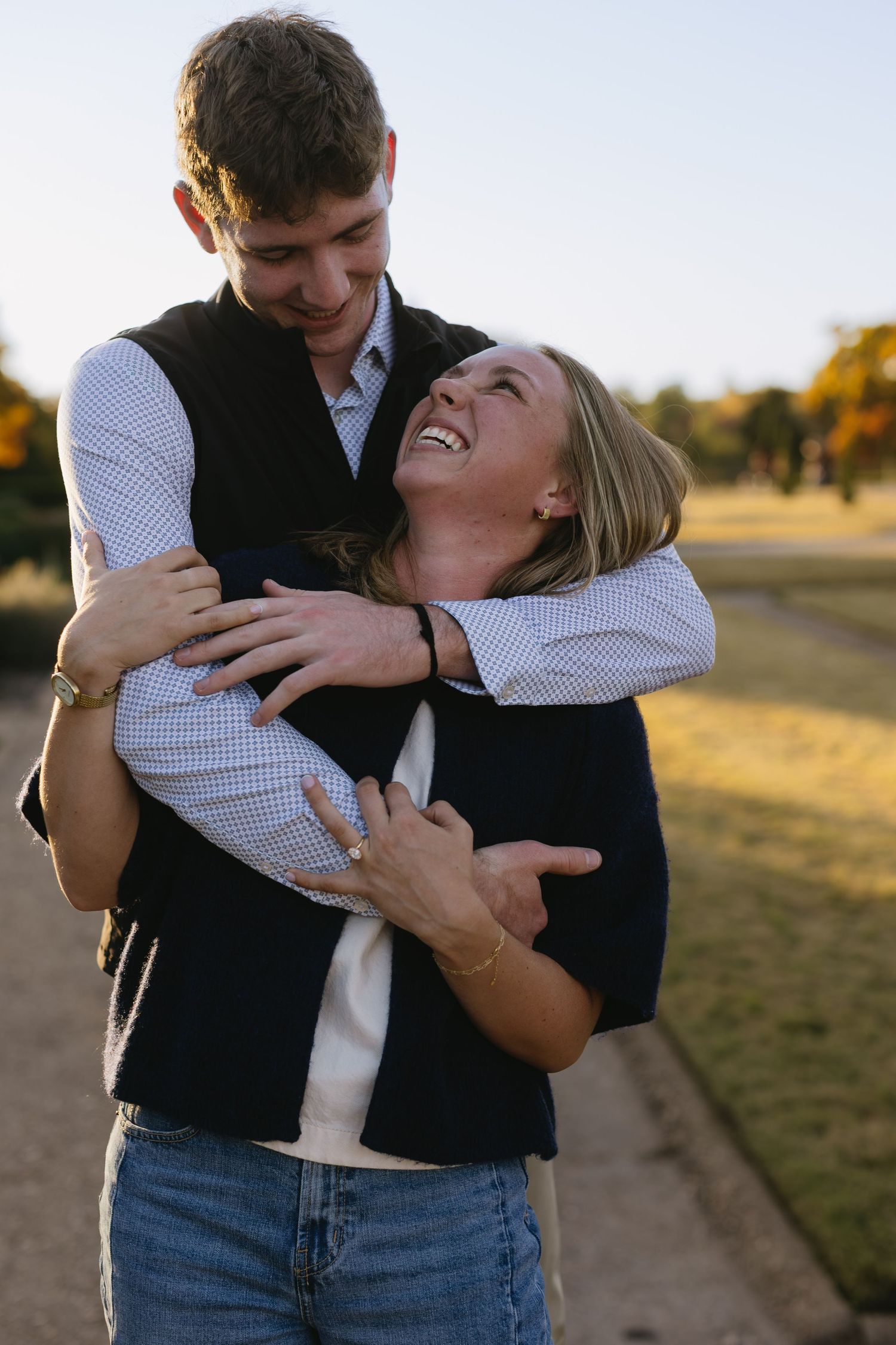 A joyful couple sharing a candid embrace in warm evening sunlight.