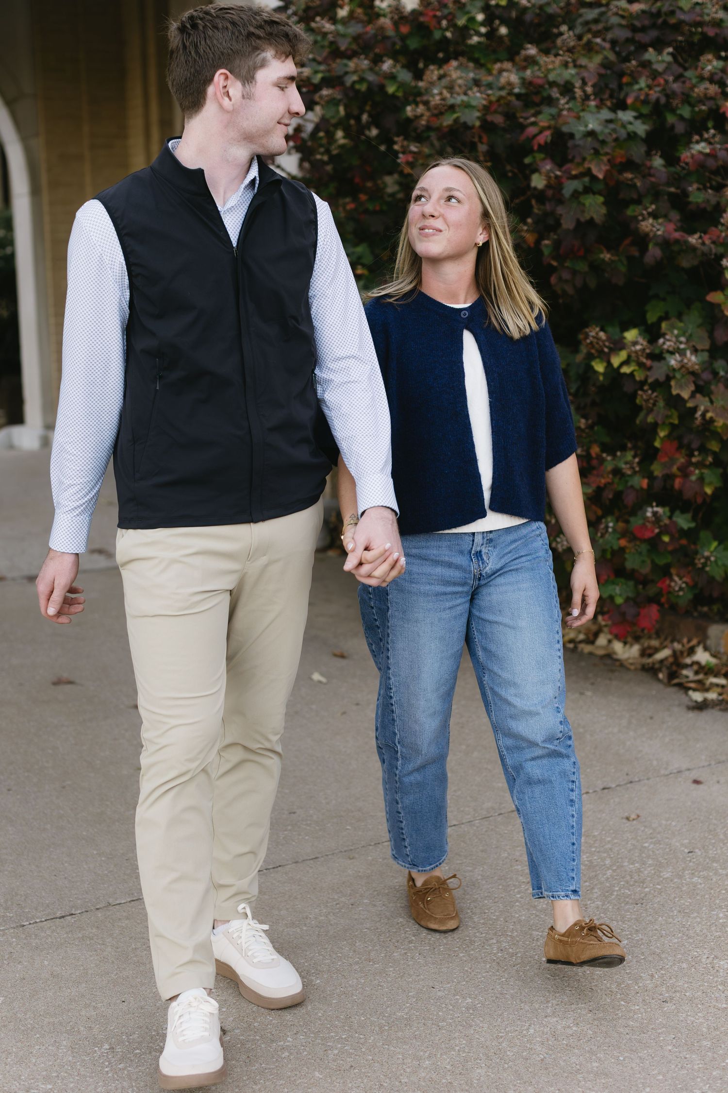 Close-up of couple's casual attire and footwear while walking together on concrete path.