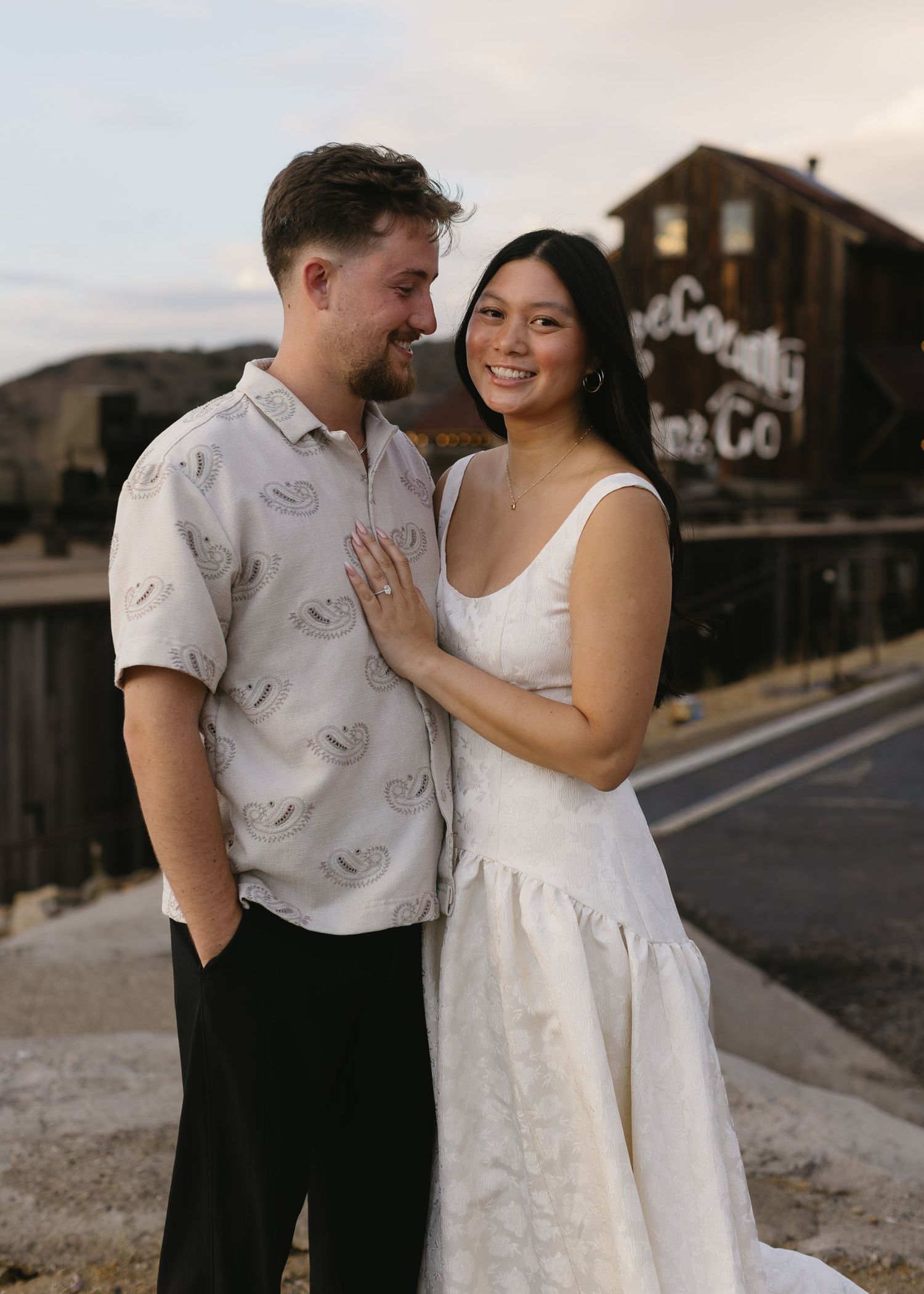Romantic engagement photo of couple in front of rustic building.