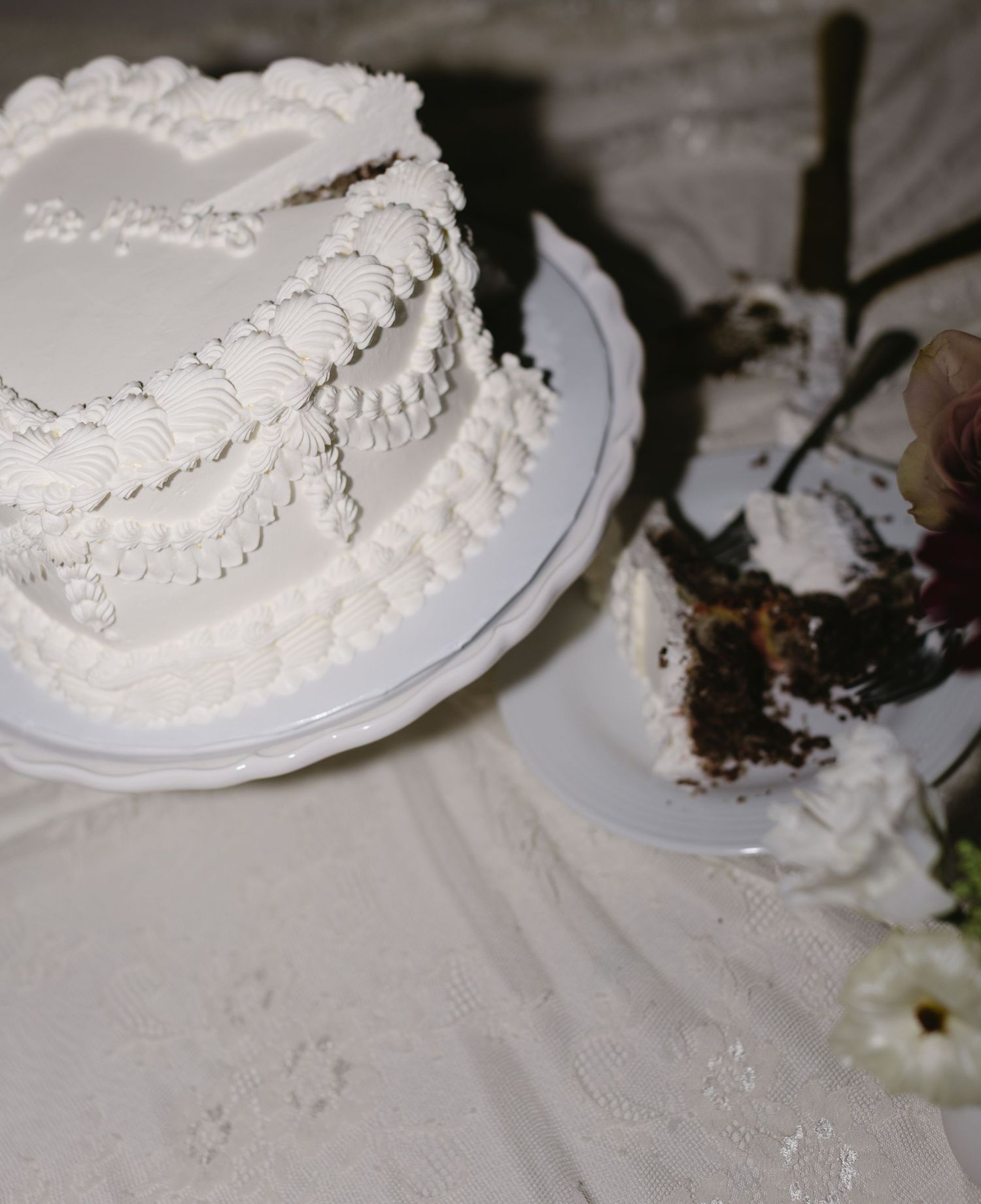Wedding cake being served on white plate with decorative frosting details.