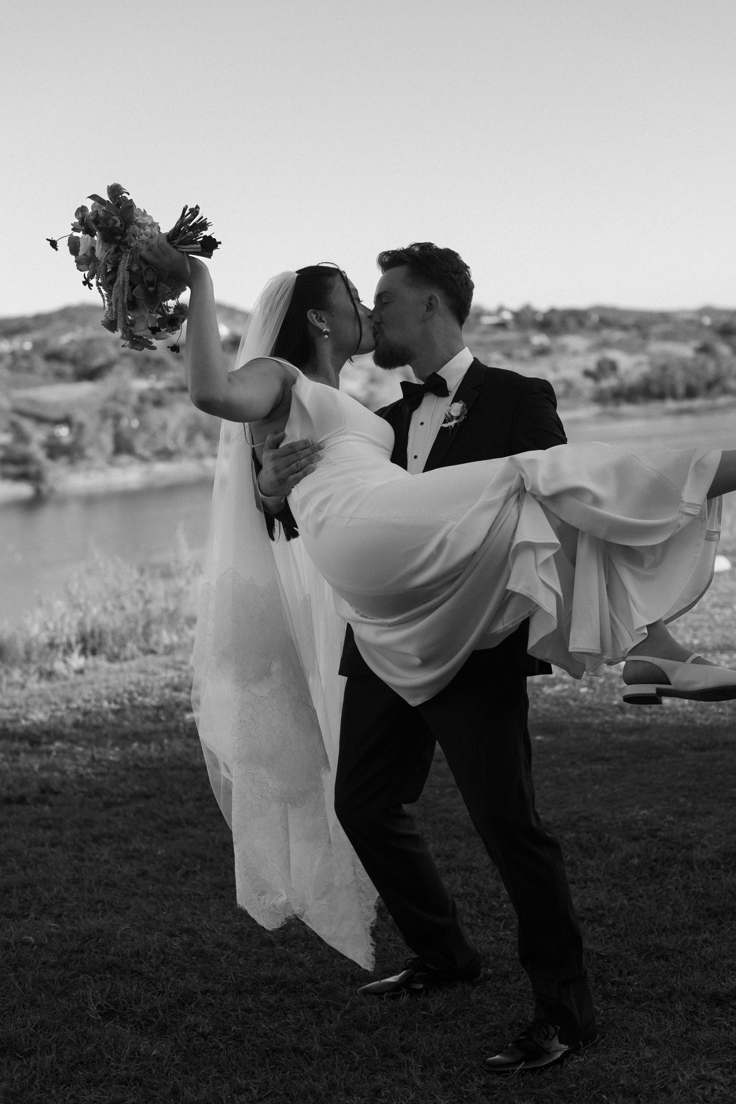 A dynamic black and white photo captures a dip during a wedding dance outdoors.