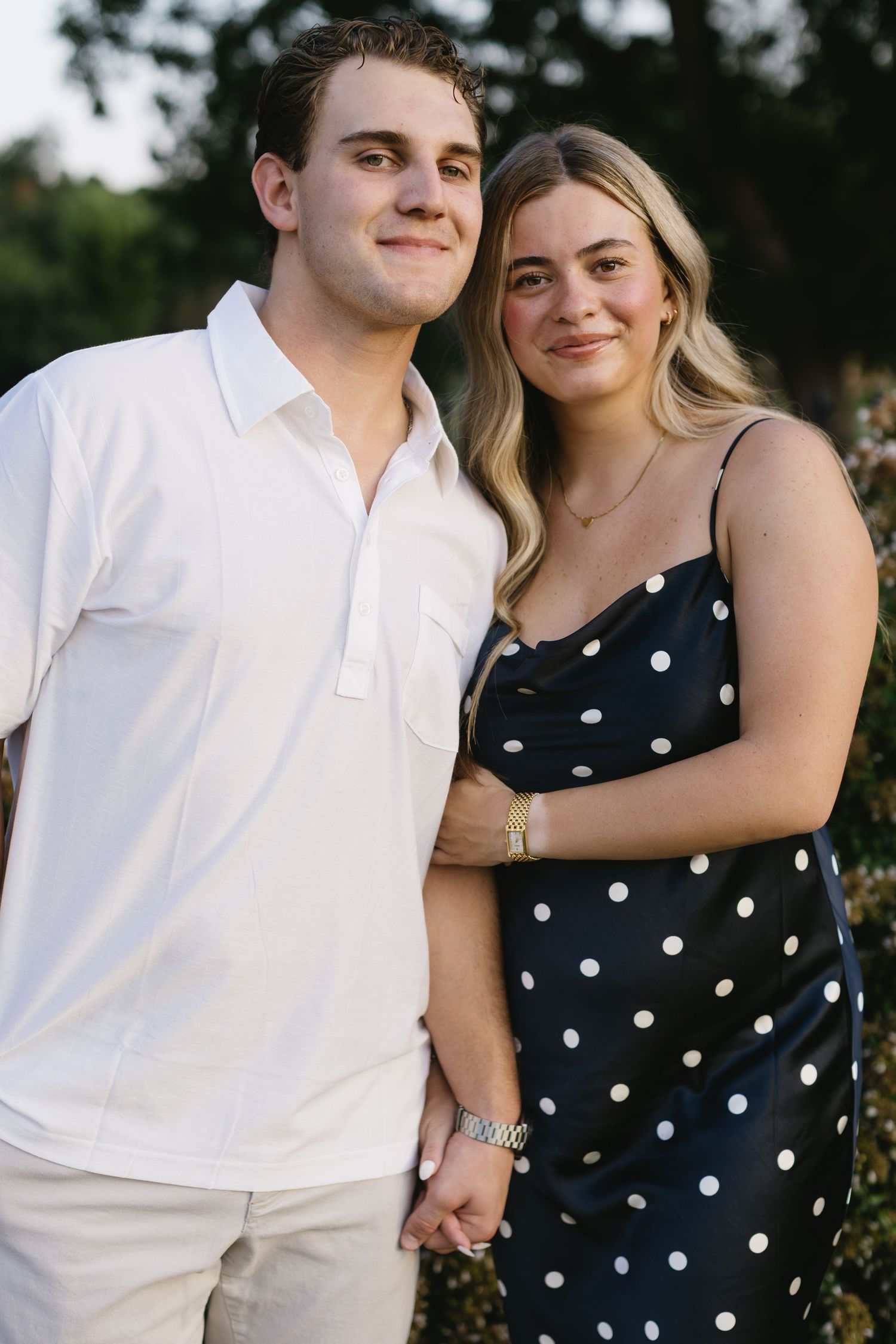 Intimate outdoor portraits featuring navy polka dots and white clothing against natural greenery.