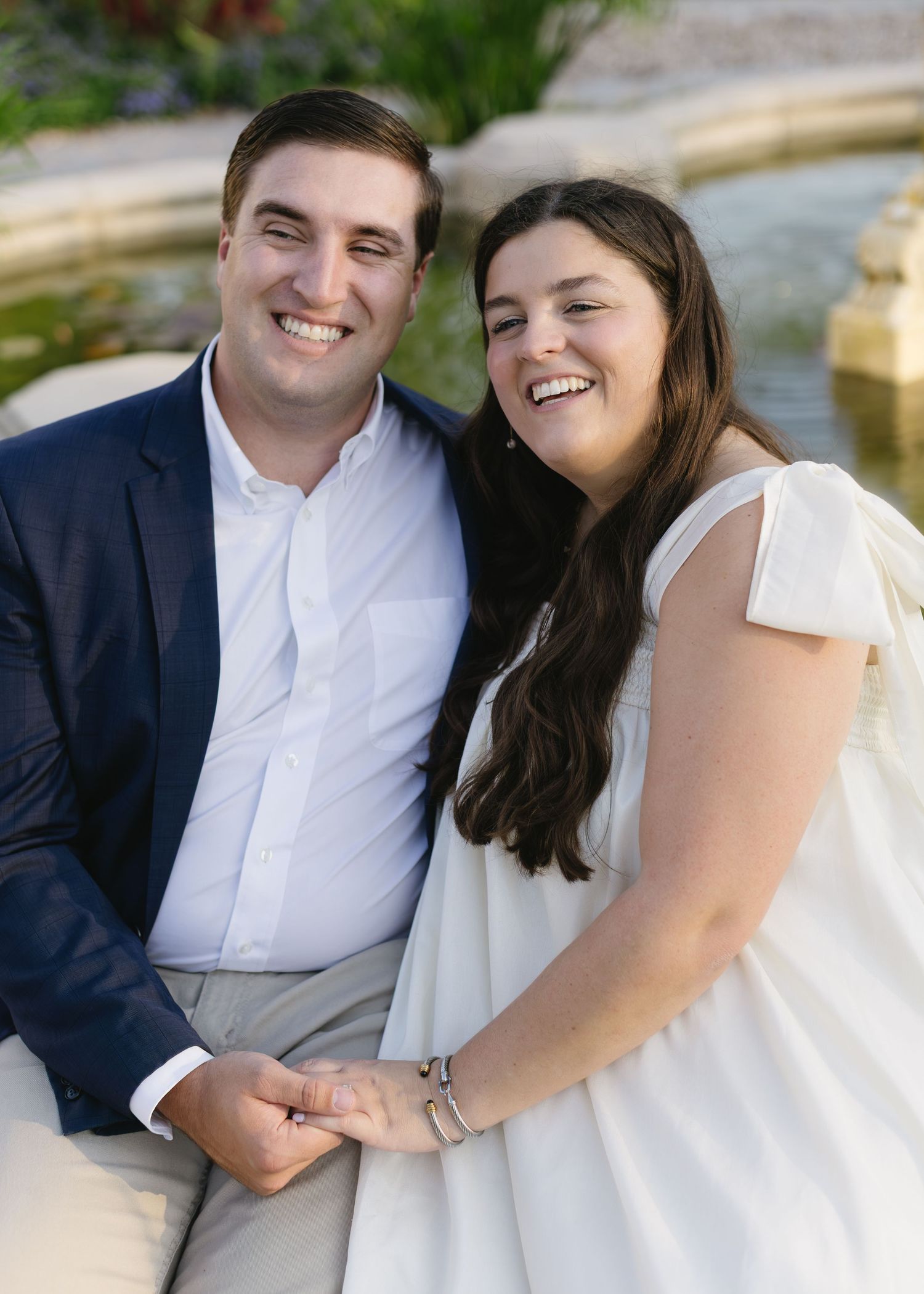 A couple shares laughter while sitting together outdoors in formal attire.