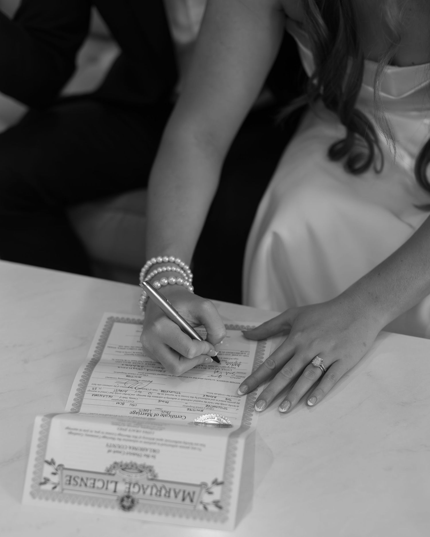 Hands signing marriage certificate during wedding ceremony.