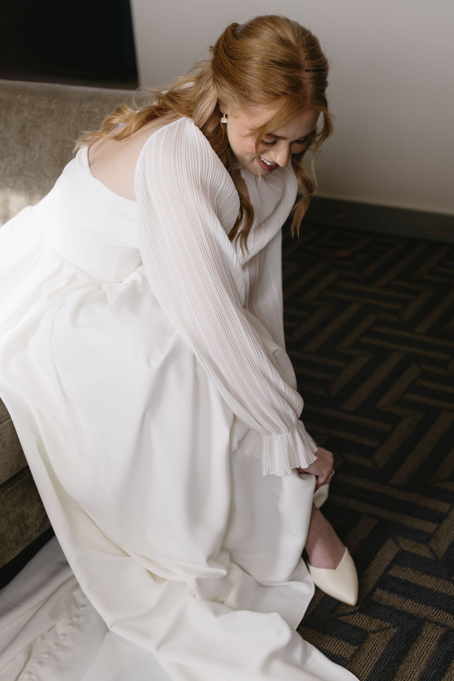 Close-up details of a white wedding dress with pleated fabric and flowing design.